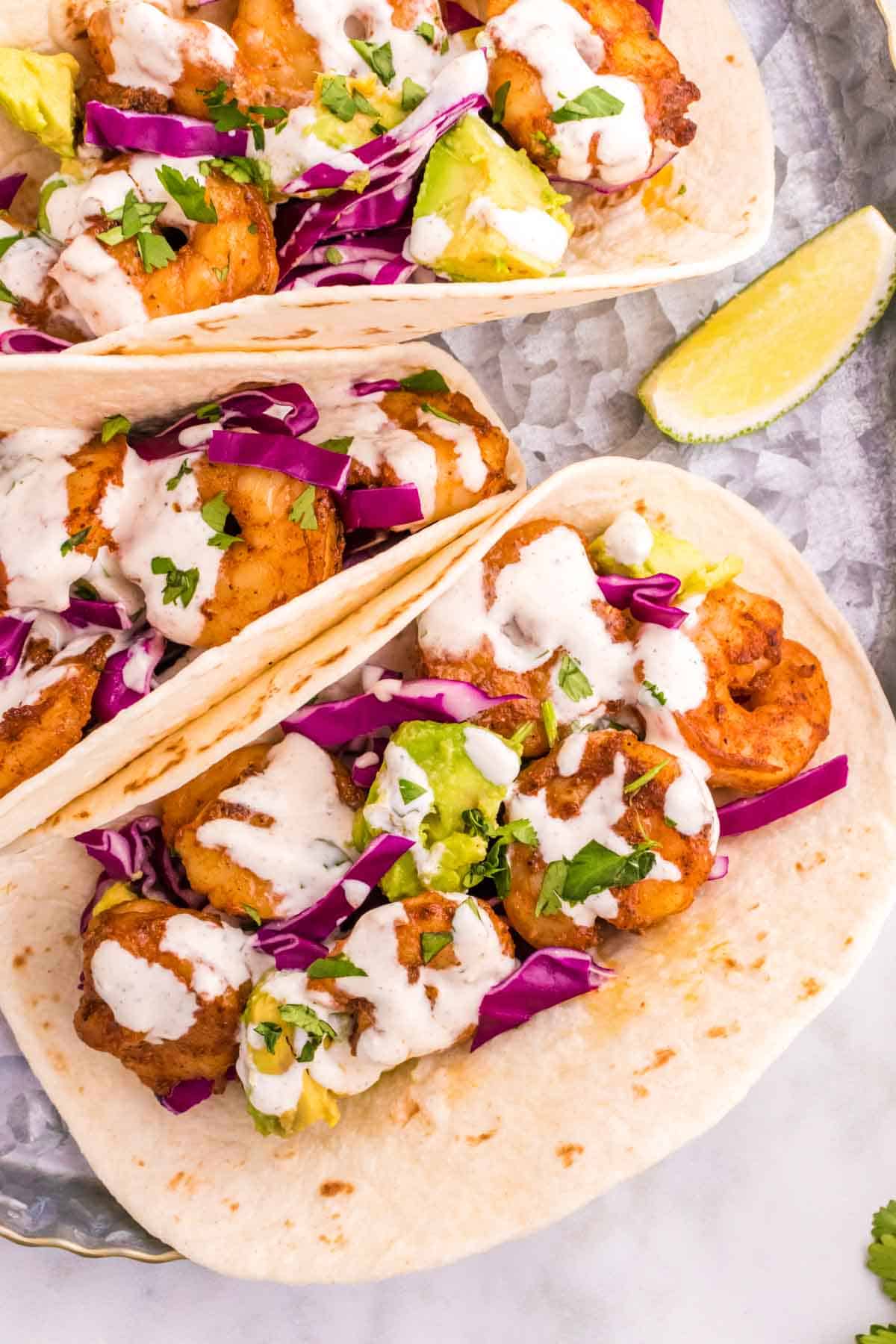 Cilantro Lime Shrimp Tacos are tasty tacos with seasoned shrimp, sliced red cabbage, diced avocados and a creamy dressing made with mayo, Greek yogurt, lime juice and cilantro.