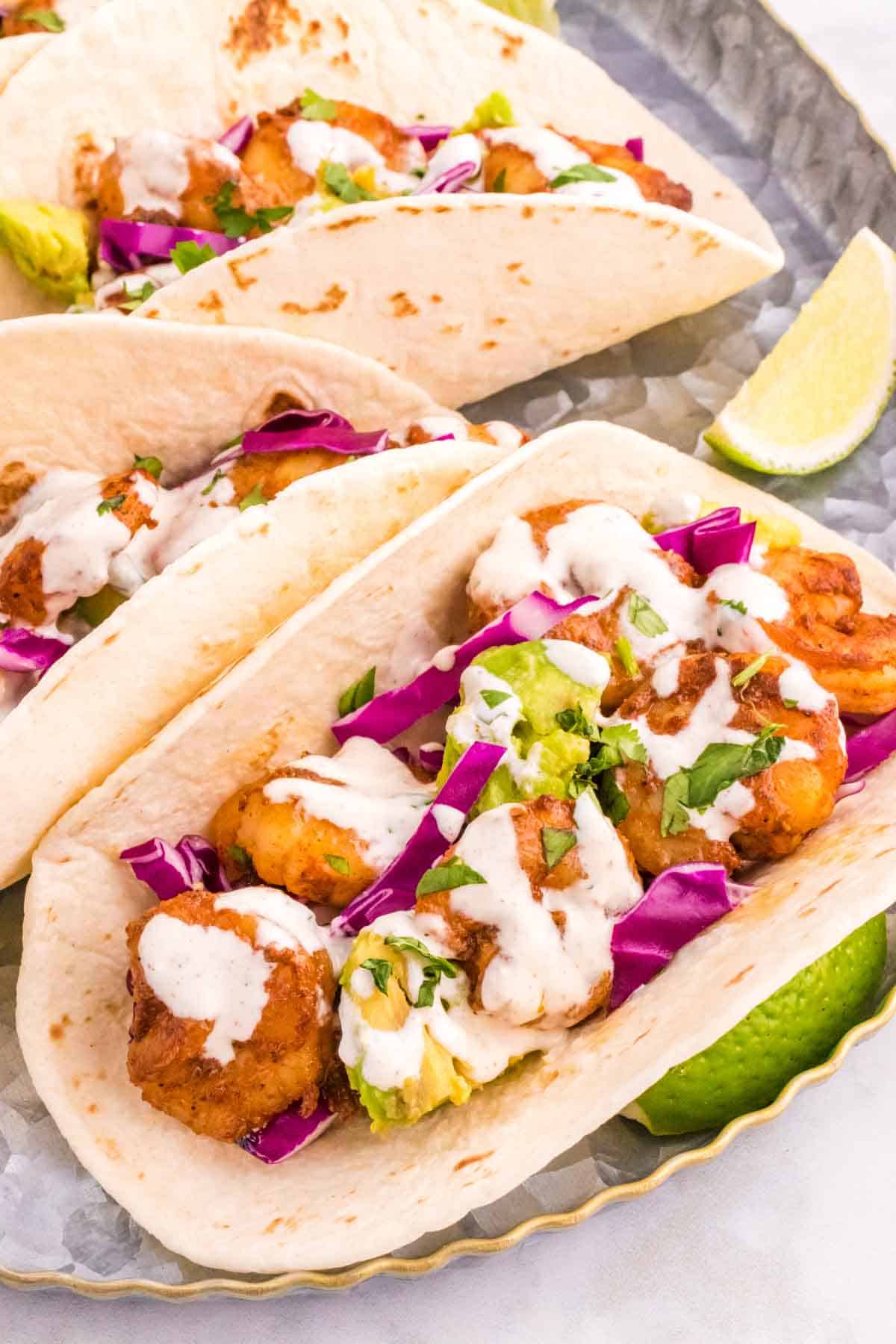 Cilantro Lime Shrimp Tacos are tasty tacos with seasoned shrimp, sliced red cabbage, diced avocados and a creamy dressing made with mayo, Greek yogurt, lime juice and cilantro.