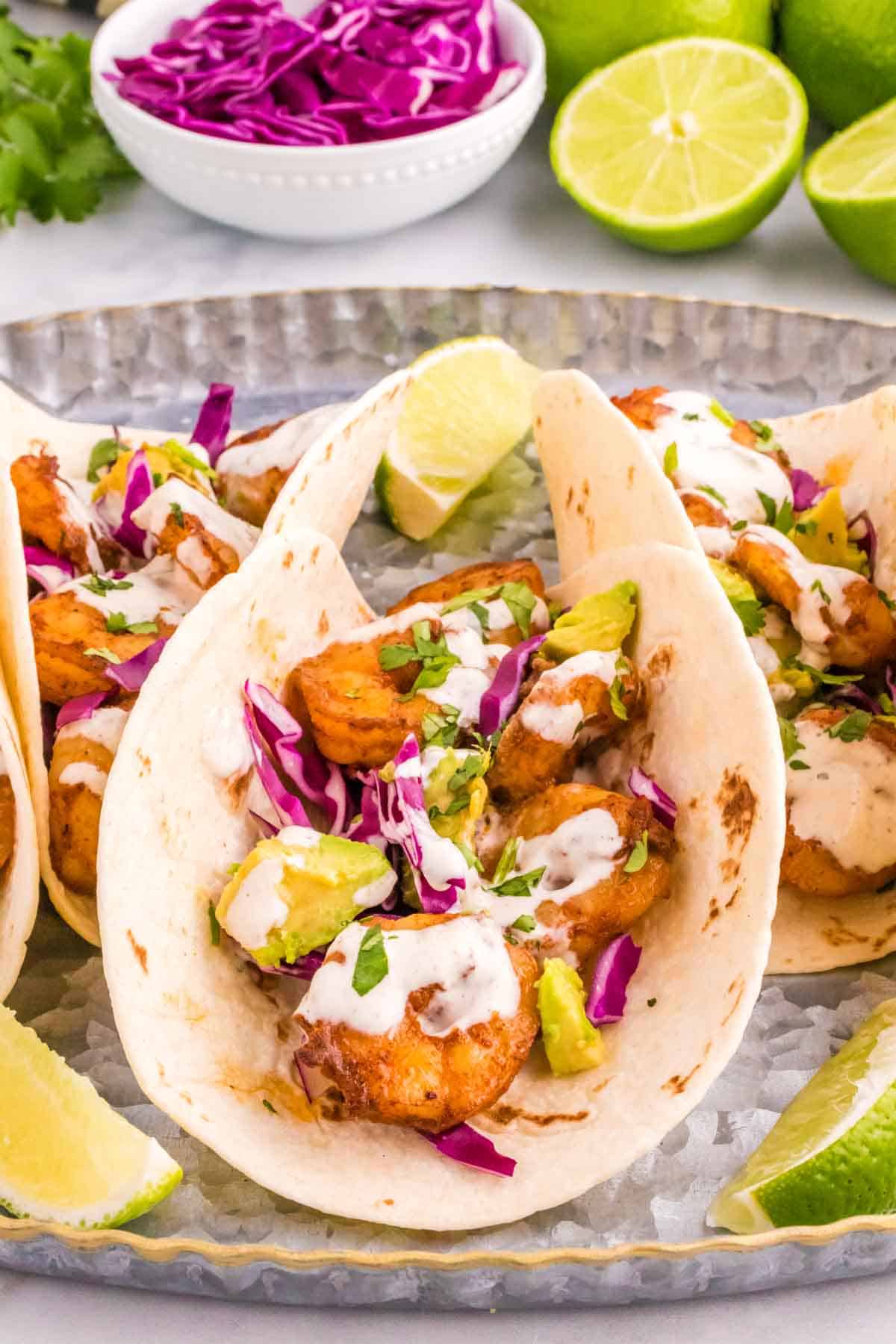 Cilantro Lime Shrimp Tacos are tasty tacos with seasoned shrimp, sliced red cabbage, diced avocados and a creamy dressing made with mayo, Greek yogurt, lime juice and cilantro.