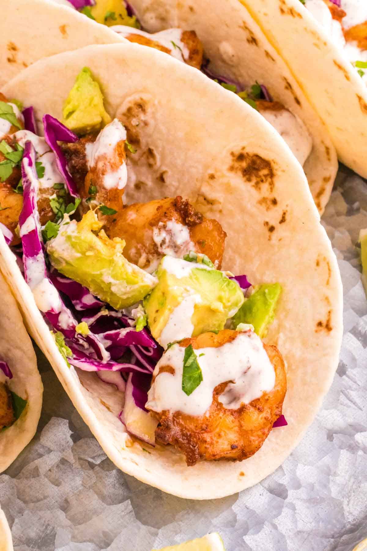 Cilantro Lime Shrimp Tacos are tasty tacos with seasoned shrimp, sliced red cabbage, diced avocados and a creamy dressing made with mayo, Greek yogurt, lime juice and cilantro.