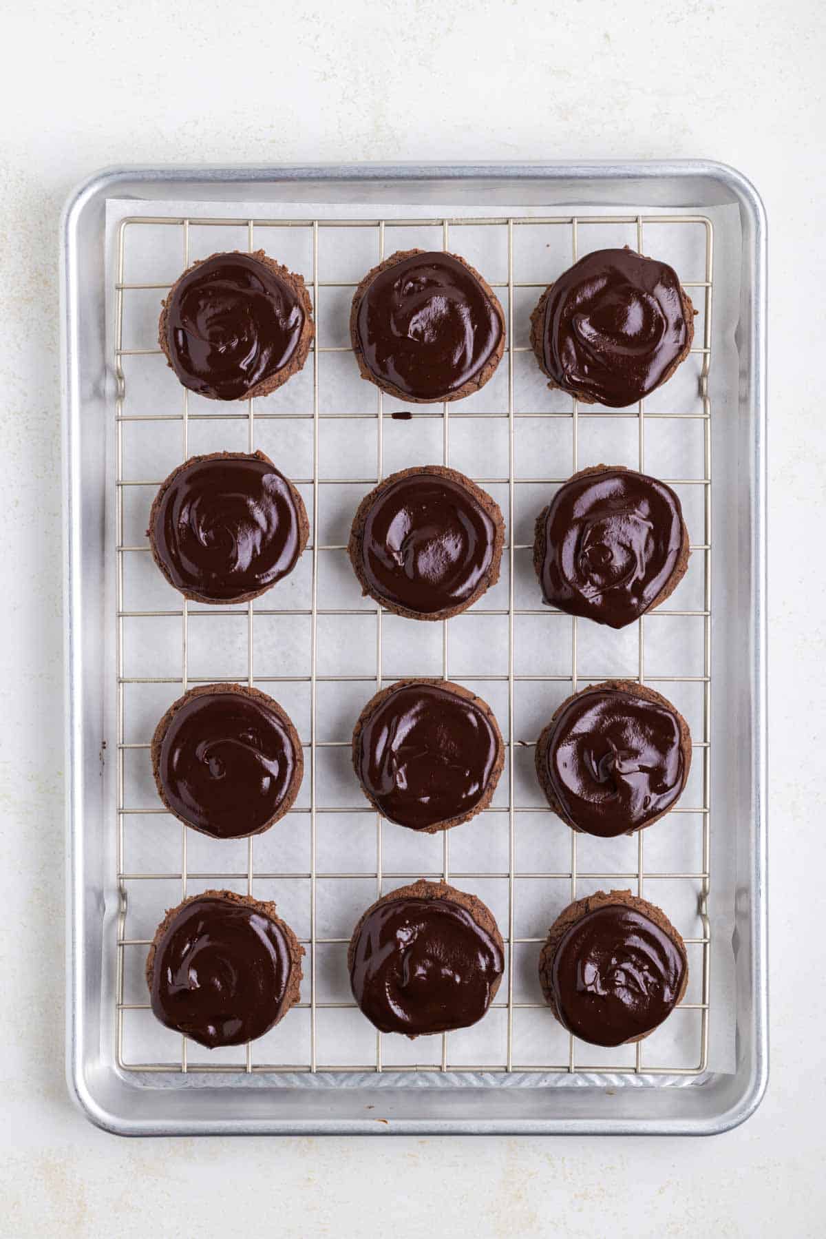 brownie cookies topped with chocolate ganache on a wired rack