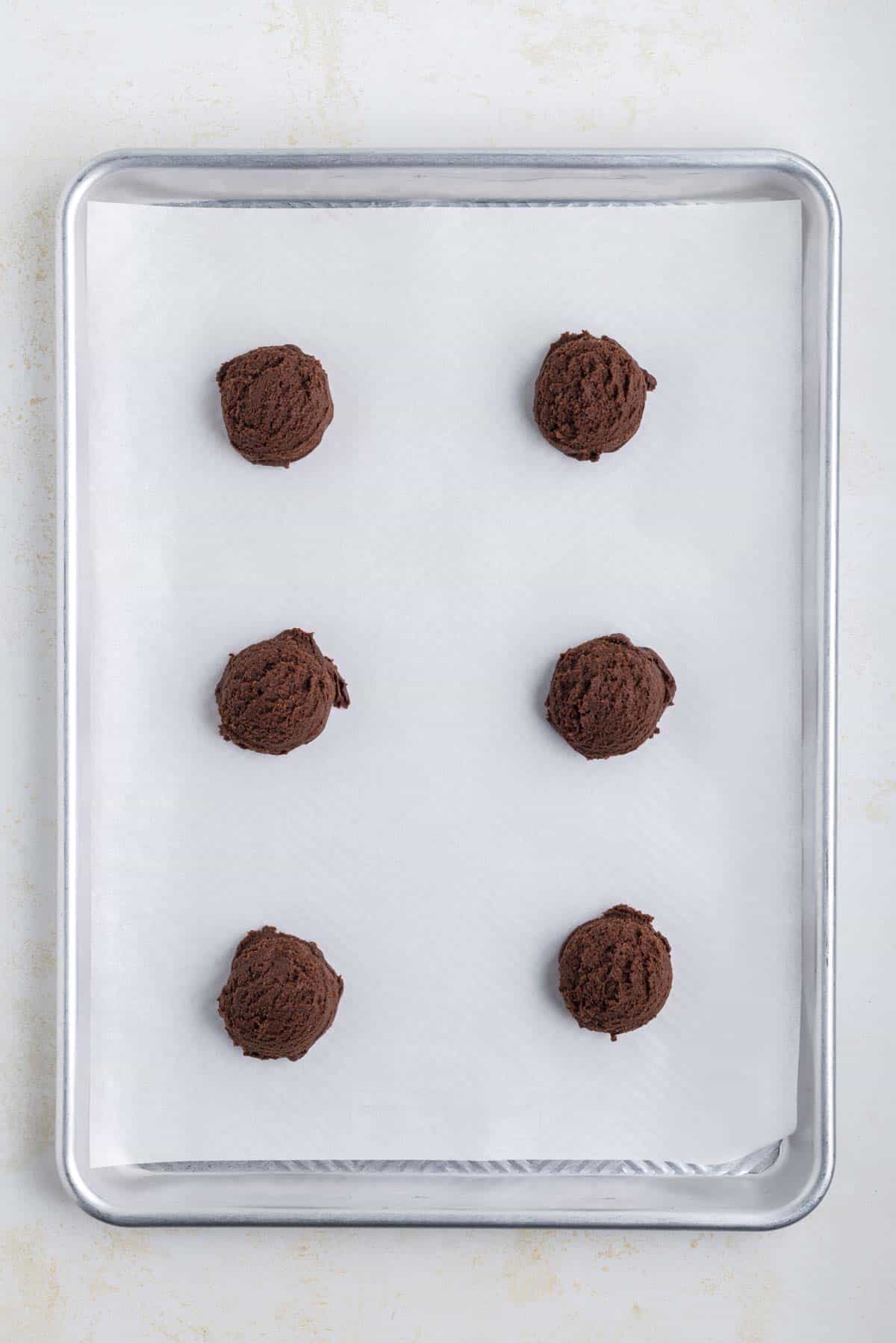 brownie cookie dough balls on a parchment lined baking sheet