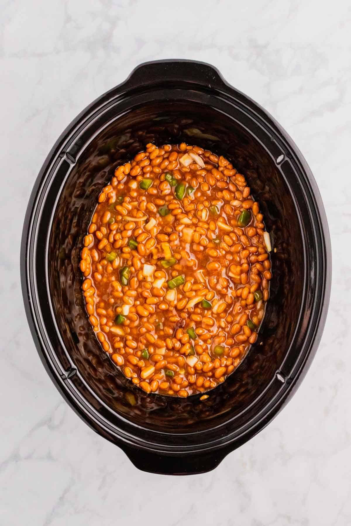 baked bean ingredients stirred together in a crock pot before cooking