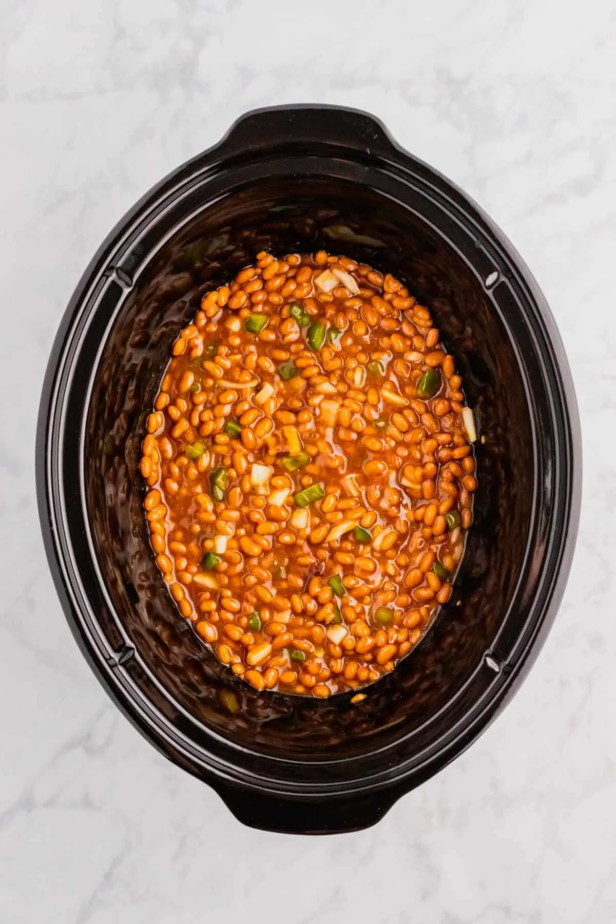 baked bean ingredients stirred together in a crock pot before cooking
