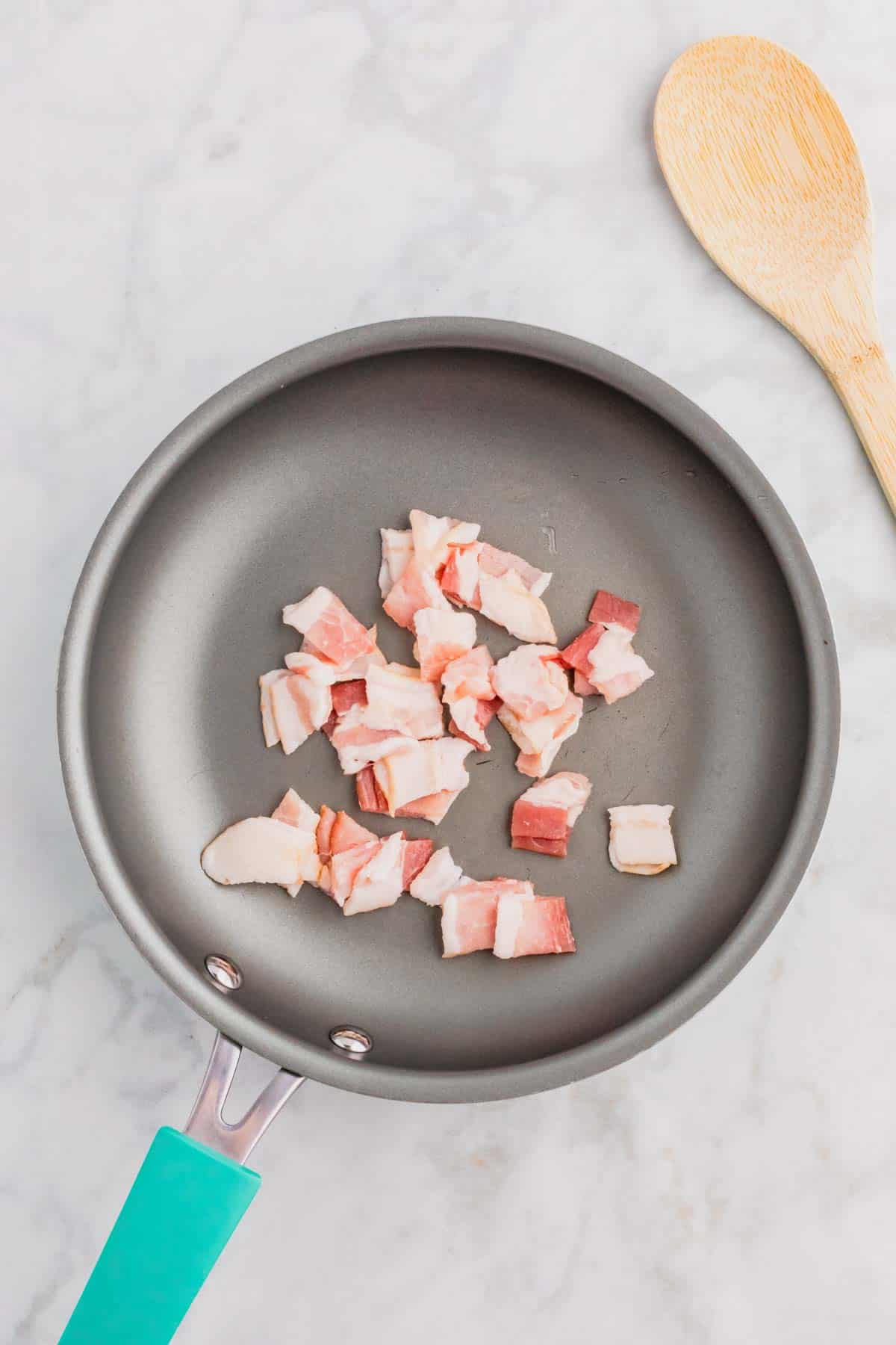 raw bacon pieces in a skillet