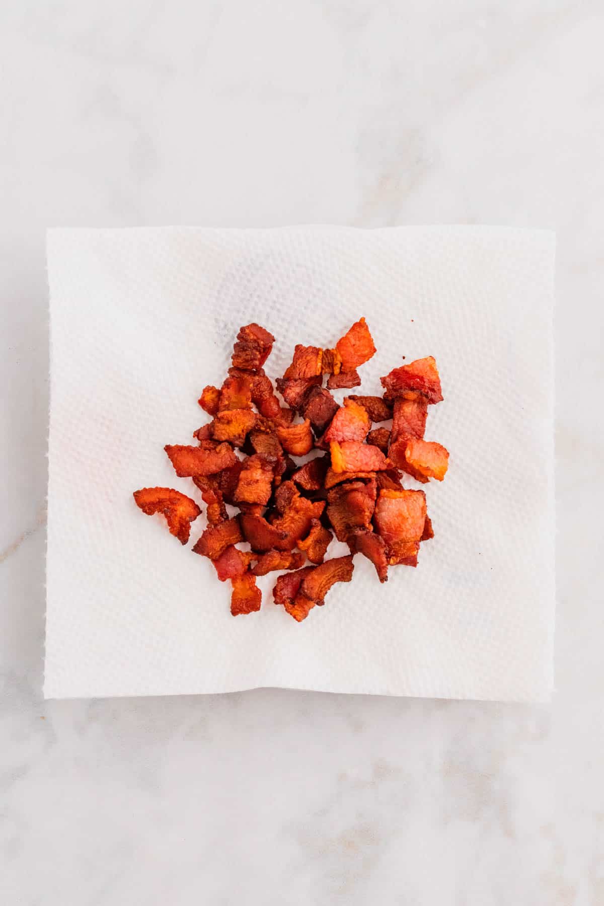cooked bacon pieces on a paper towel lined plate