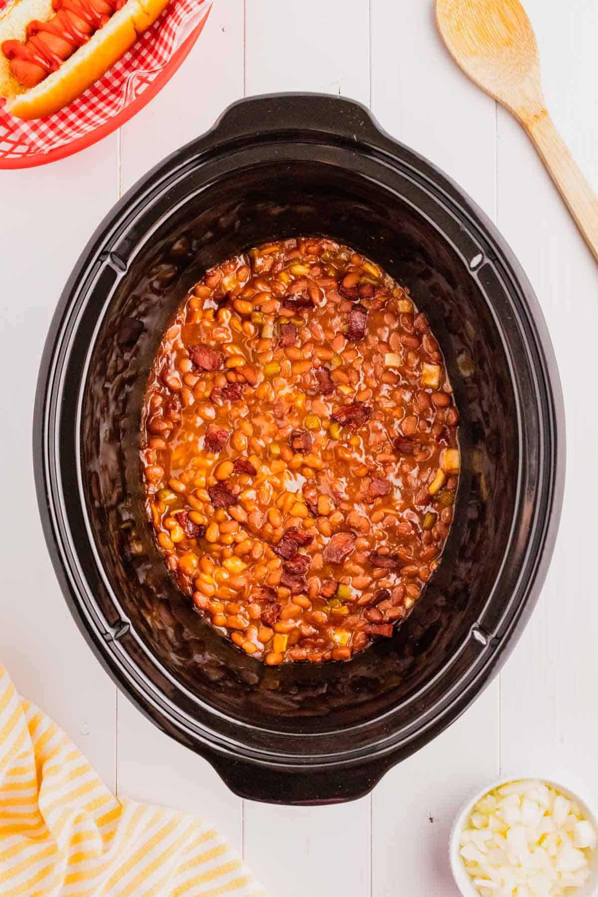 Crock Pot Baked Beans are a simple slow cooker side dish recipe made with canned baked beans, barbecue sauce, ketchup, brown sugar, bell peppers, onions and bacon.