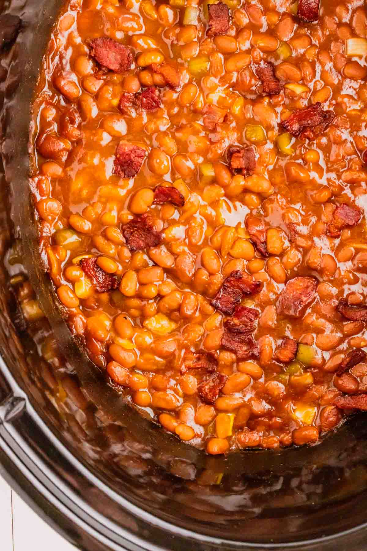 Crock Pot Baked Beans are a simple slow cooker side dish recipe made with canned baked beans, barbecue sauce, ketchup, brown sugar, bell peppers, onions and bacon.