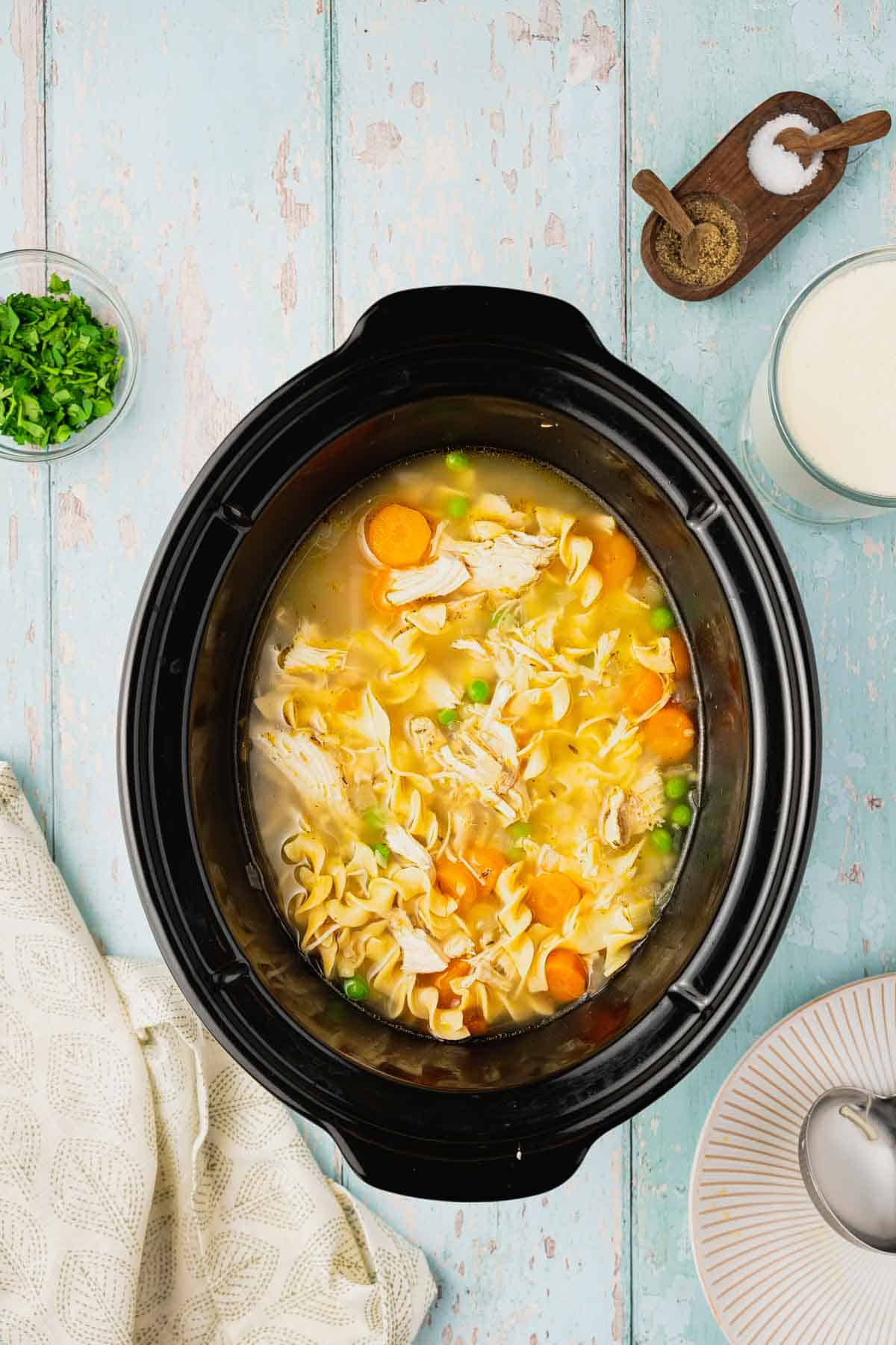 noodles, chicken and veggies in broth in a slow cooker