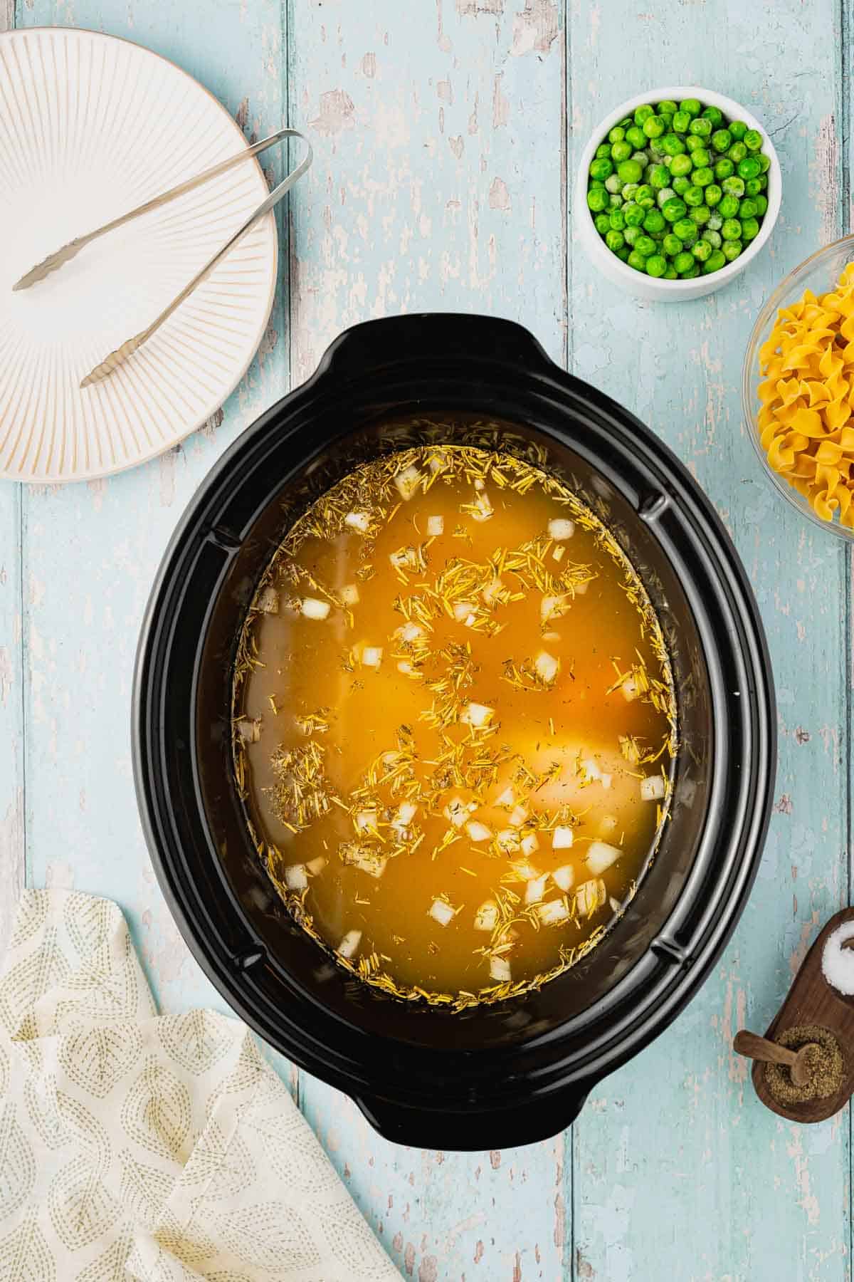 chicken broth added to crock pot with chicken breasts and veggies