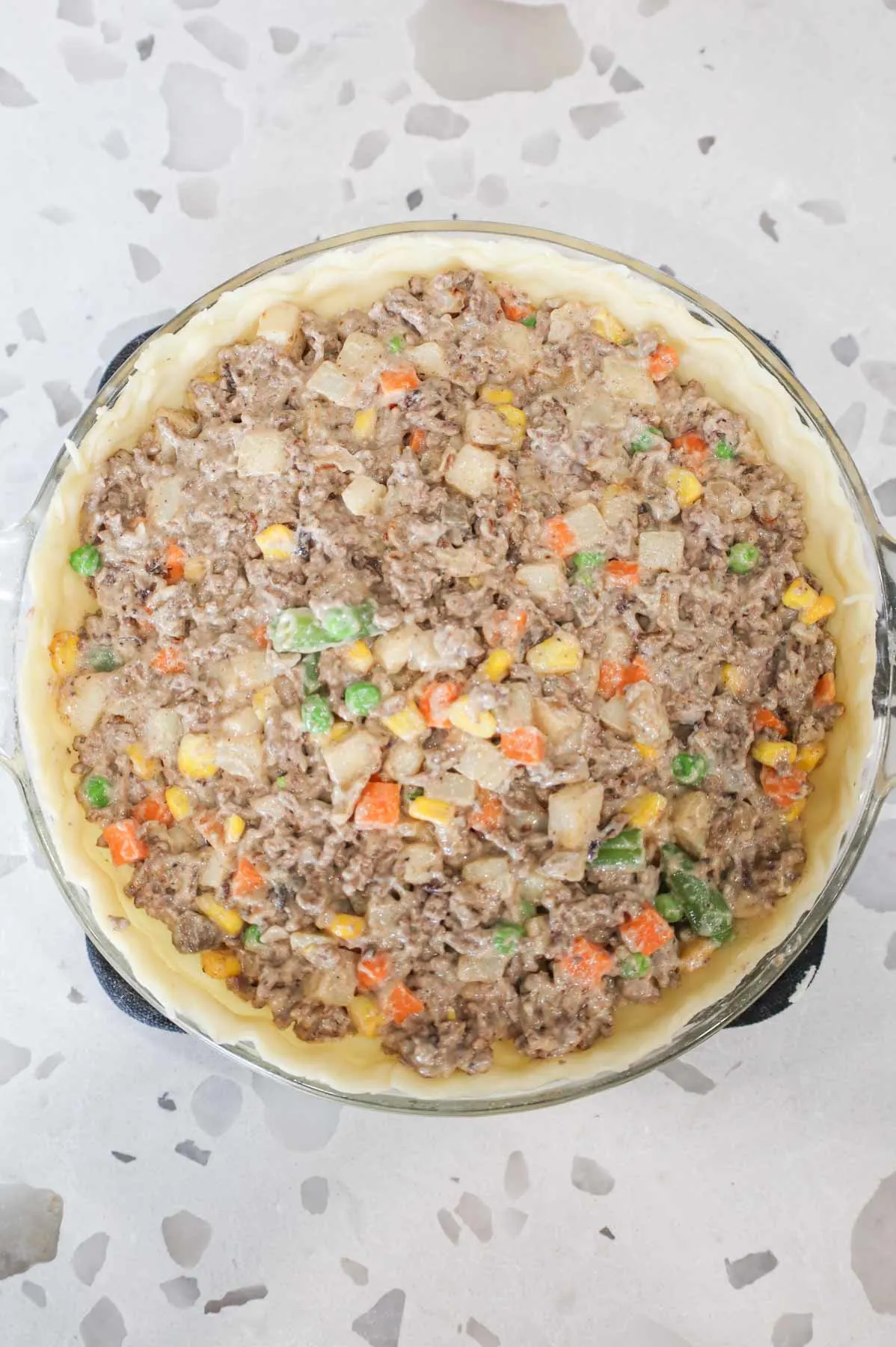 ground beef and veggie mixture in a pie crust in a pie plate