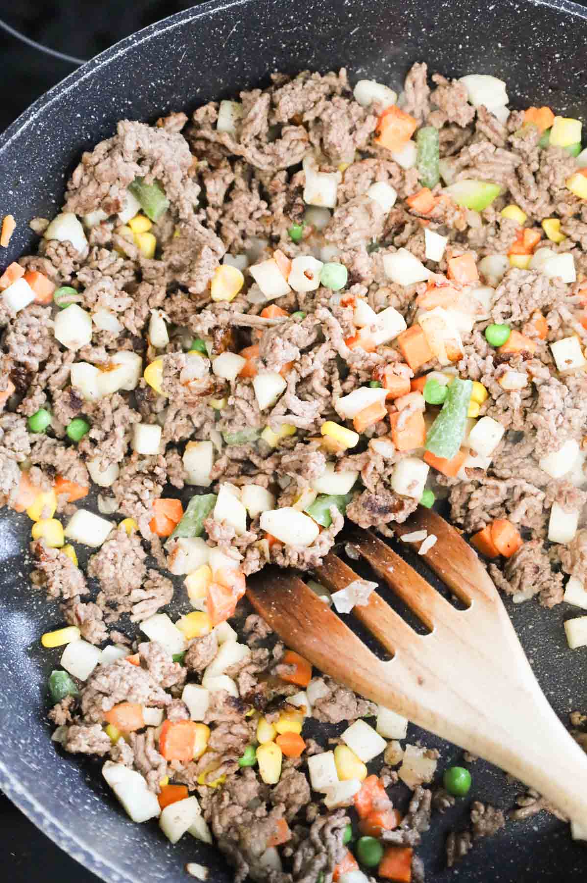 ground beef and mixed veggies cooking in a skillet