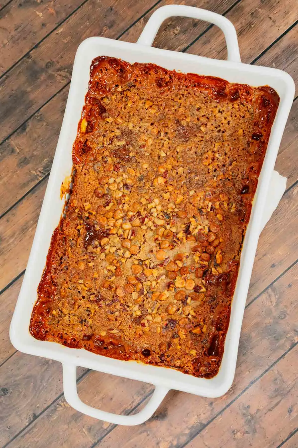 Carrot Dump Cake is an easy and decadent dessert recipe using freshly grated carrot, canned dulce de leche, store bought cream cheese frosting, boxed carrot cake mix, cream cheese flavoured baking chips, chopped pecans and melted butter.