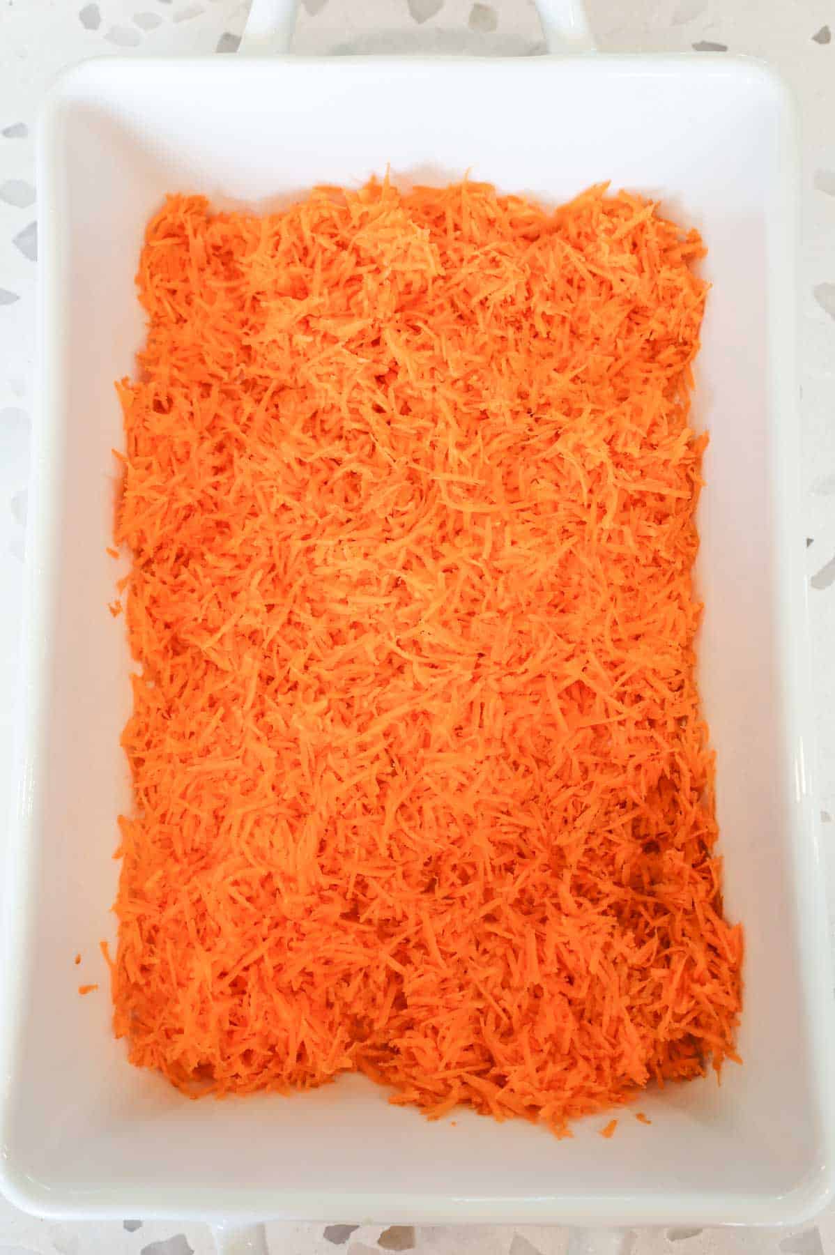 grated carrot in the bottom of a baking dish