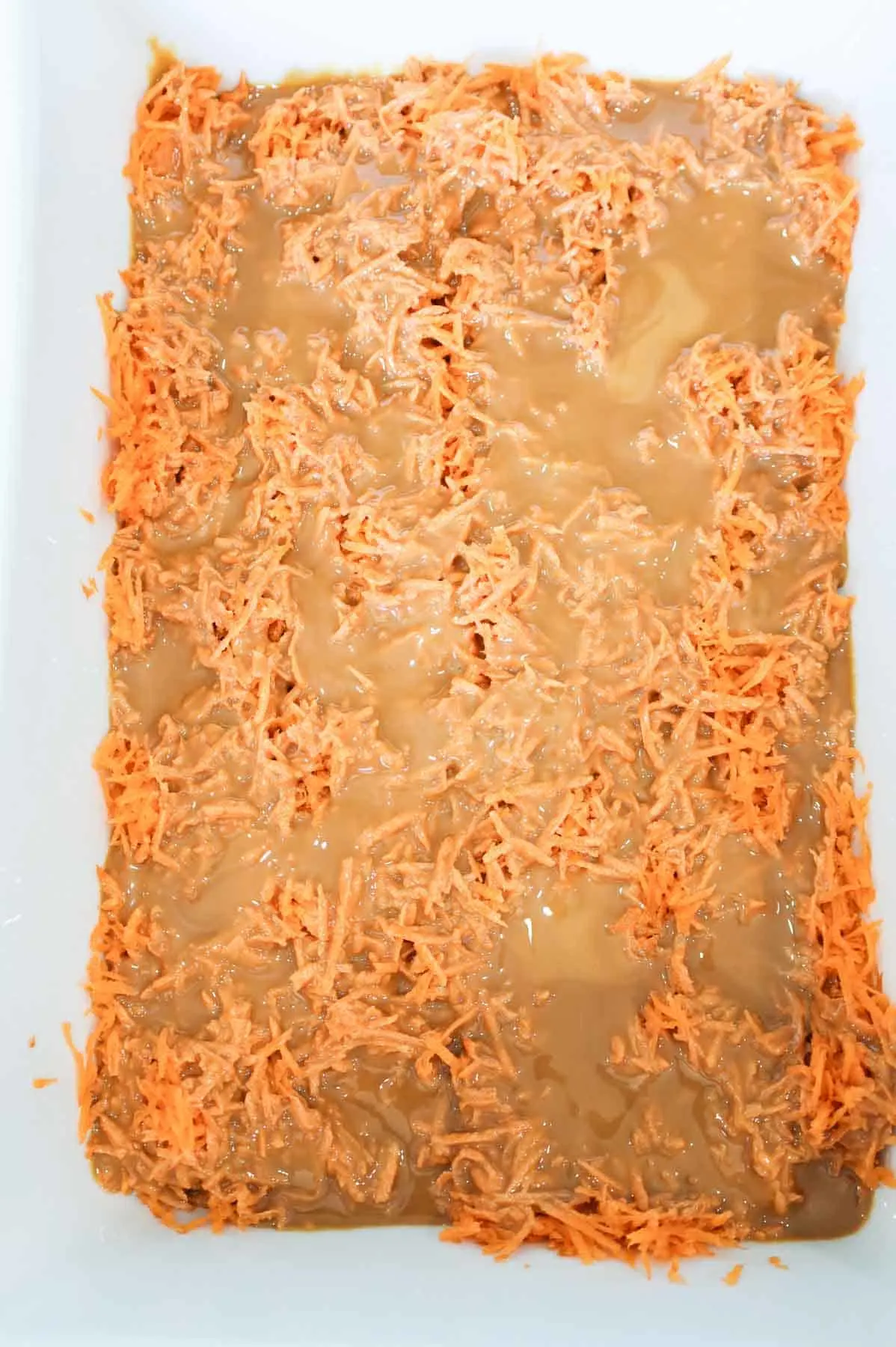 dulce de leche poured over grated carrot in a baking dish