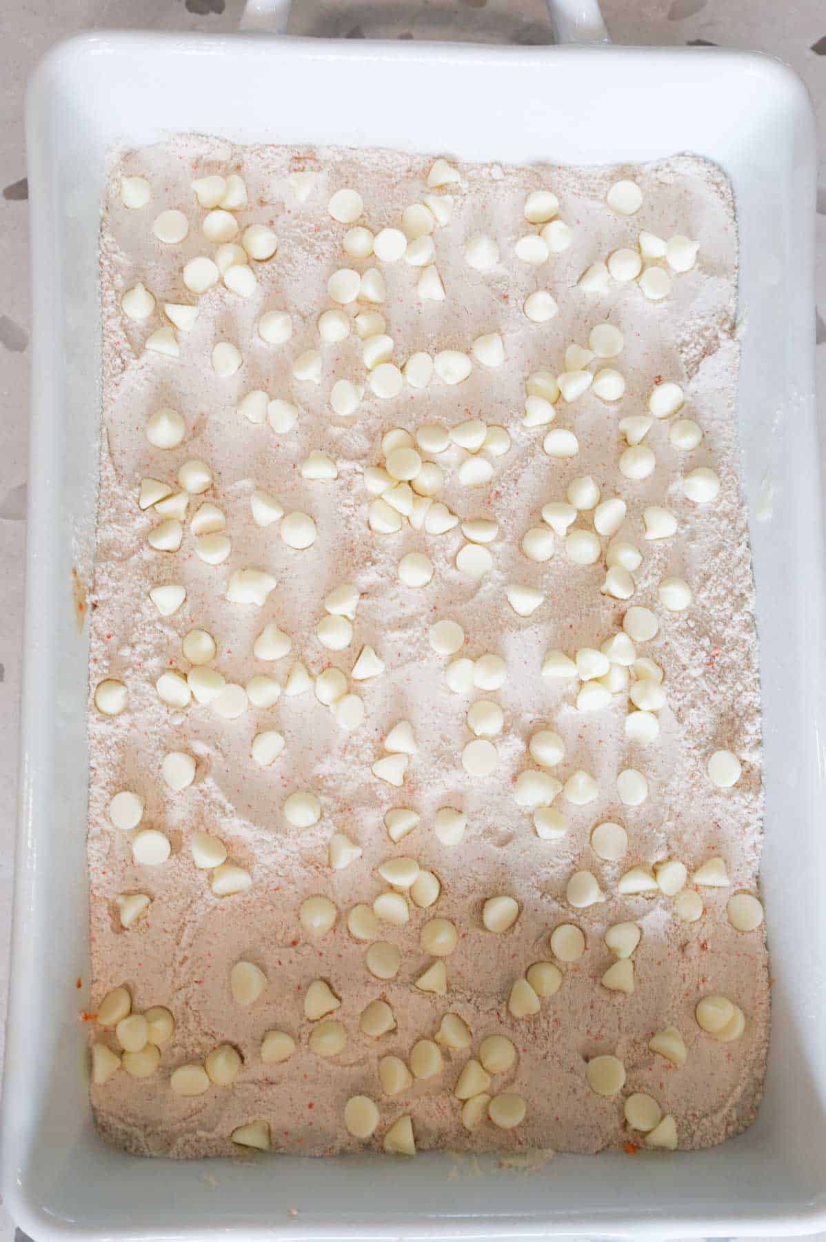 cream cheese flavoured baking bits on top of dry carrot cake mix in a baking dish