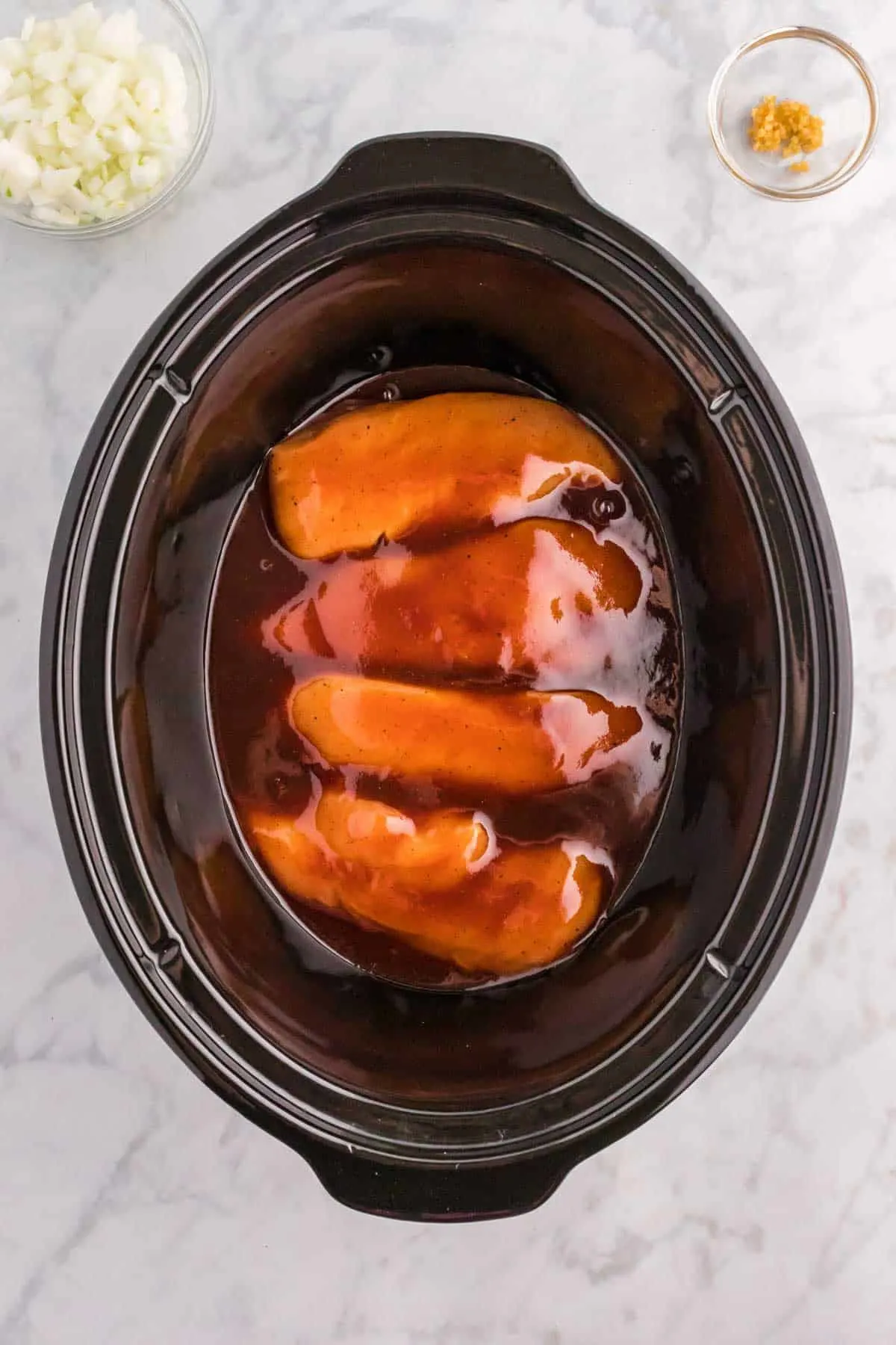 raw chicken breasts in BBQ sauce mixture in a Crock Pot