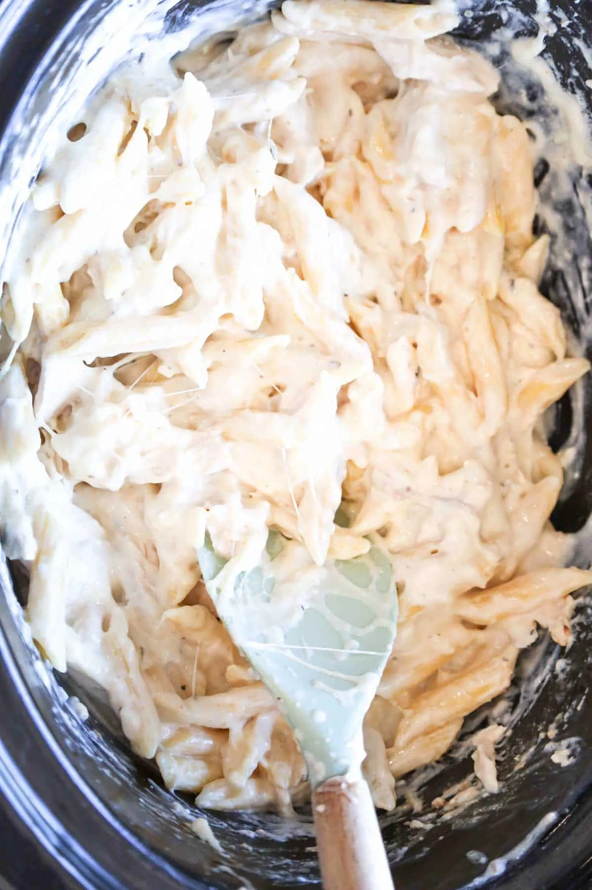 stirring cheese into creamy pasta in a crock pot