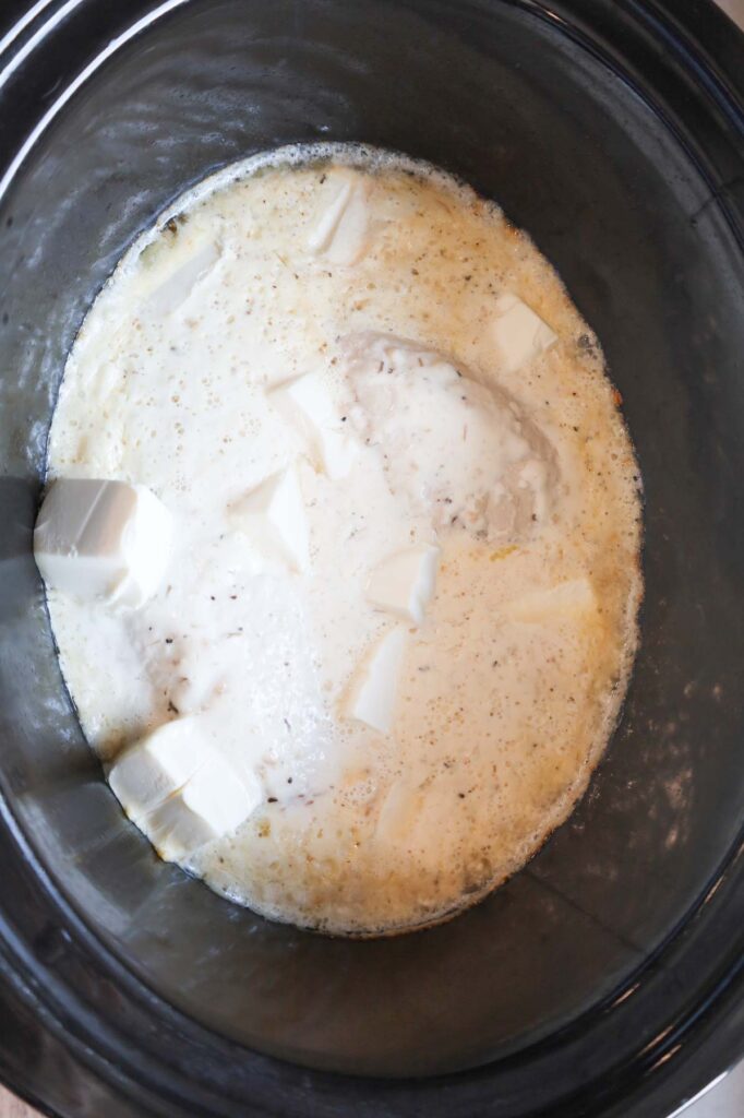 cooked chicken breasts in a creamy sauce in a crock pot