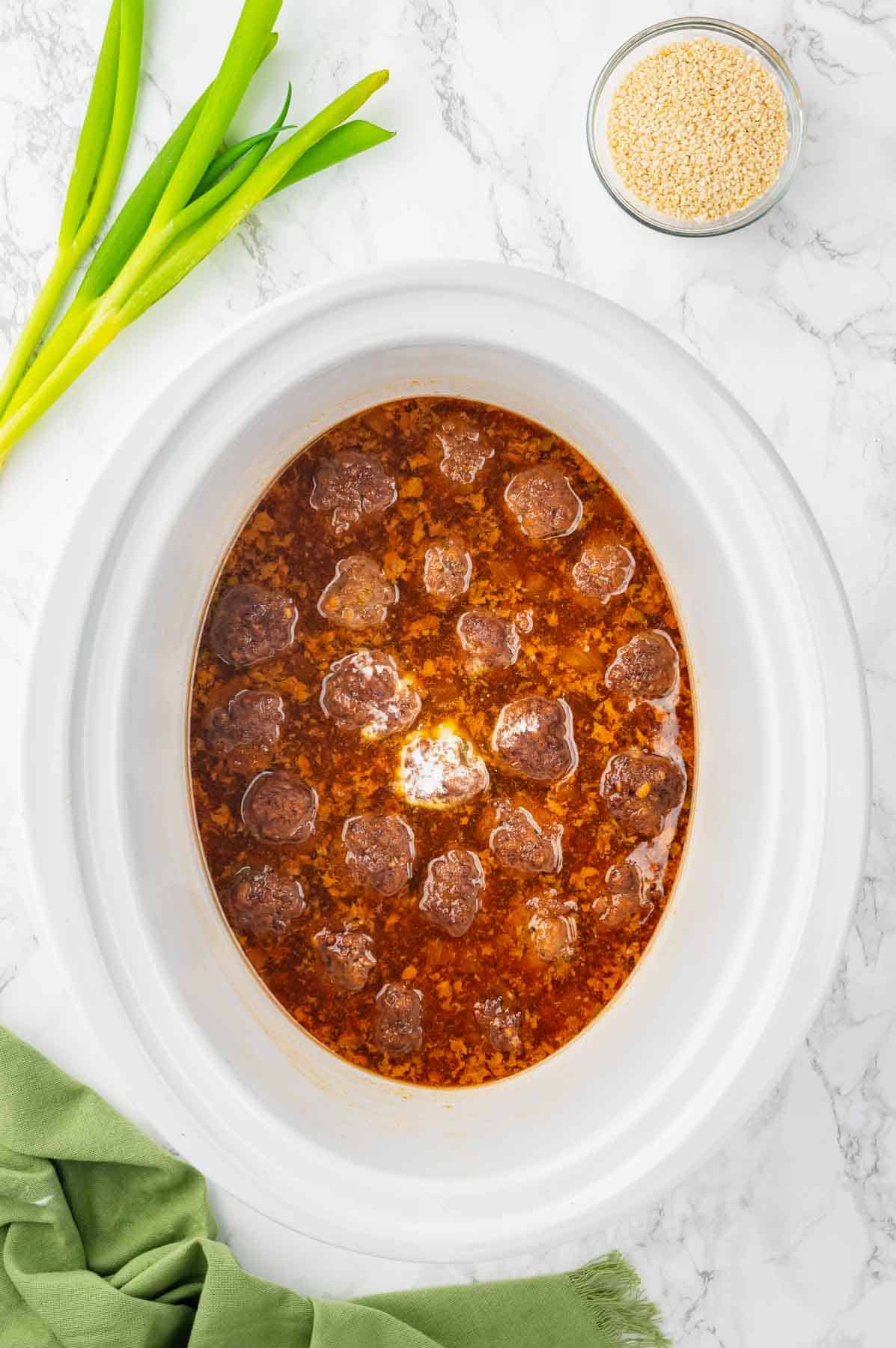 cornstarch slurry added to crock pot with teriyaki meatballs while cooking