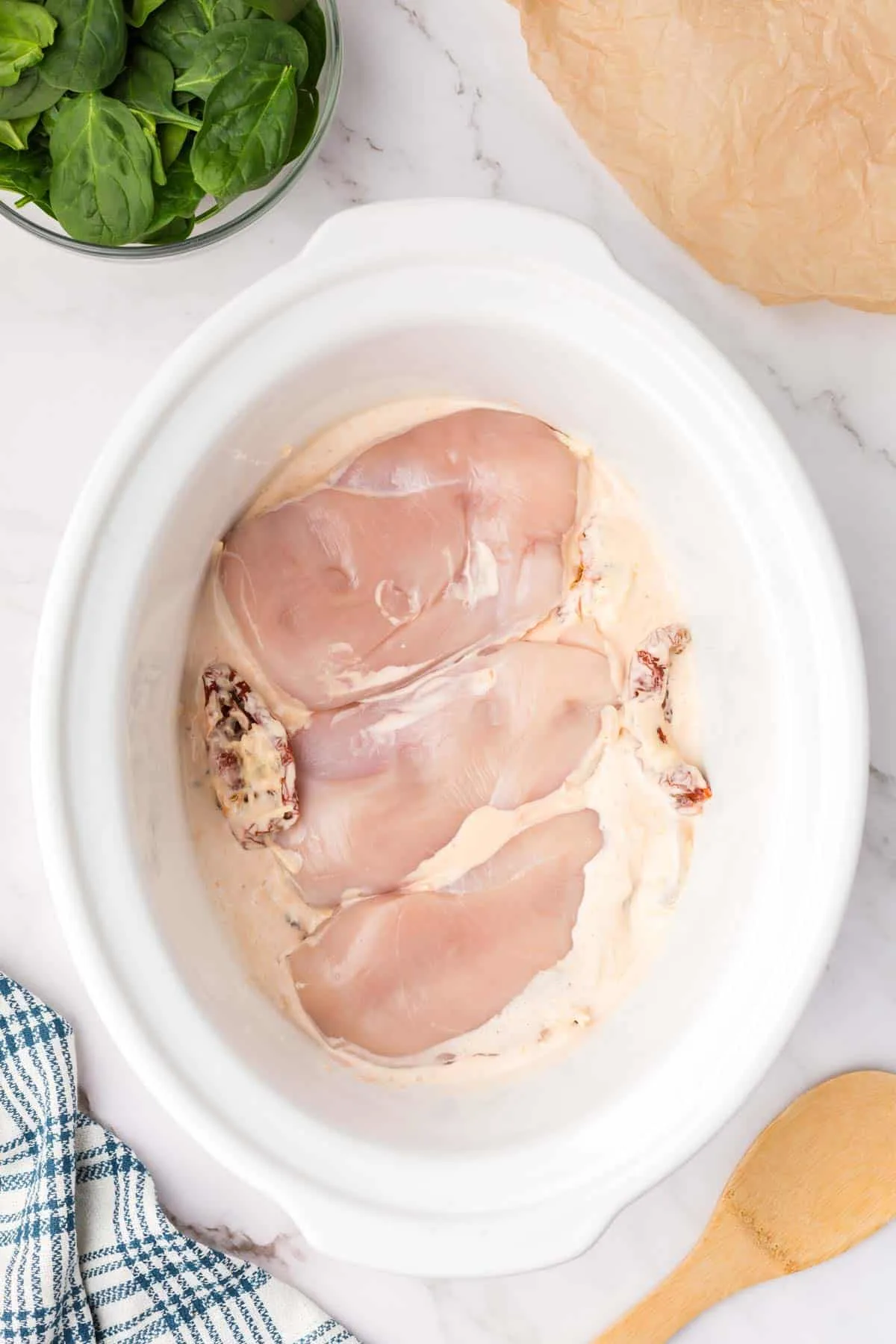 boneless, skinless chicken breasts on top of creamy sauce mixture in a crock pot