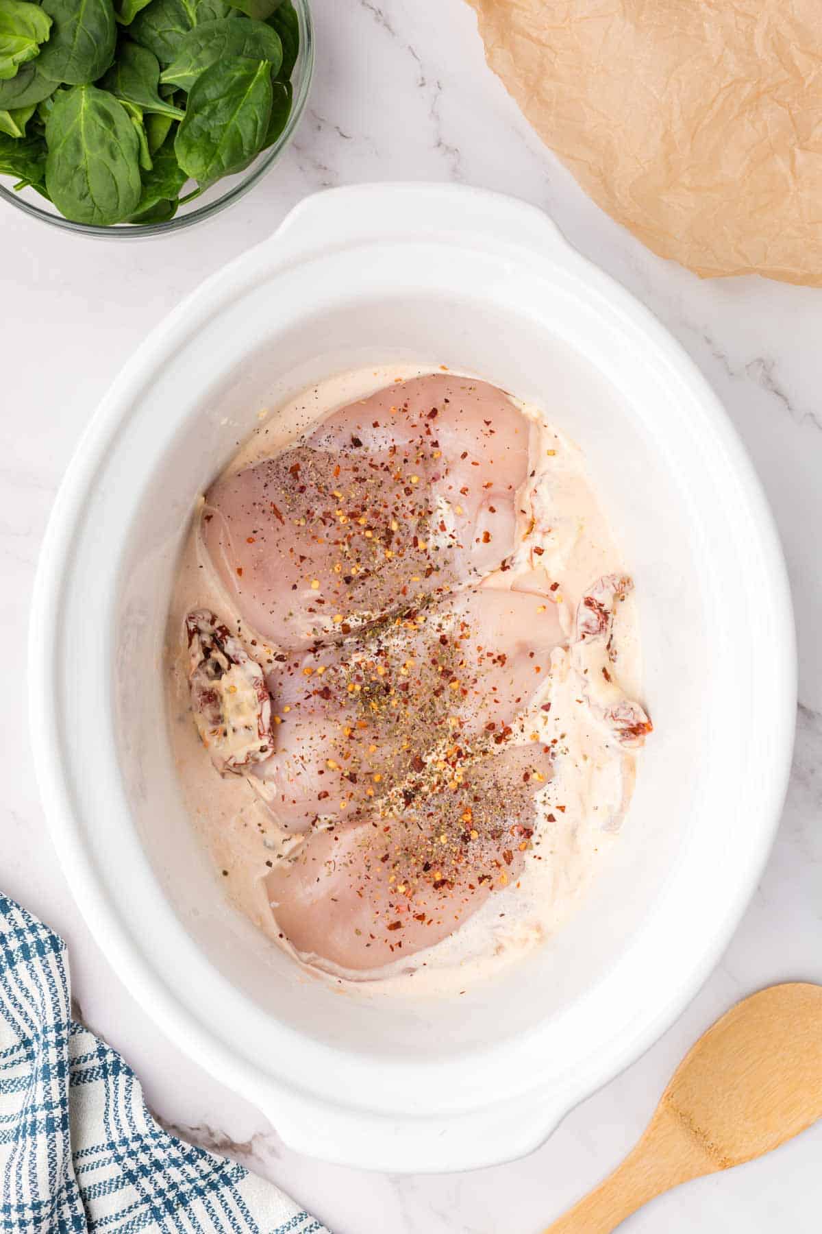 seasoning on top of boneless, skinless chicken breasts in a crock pot