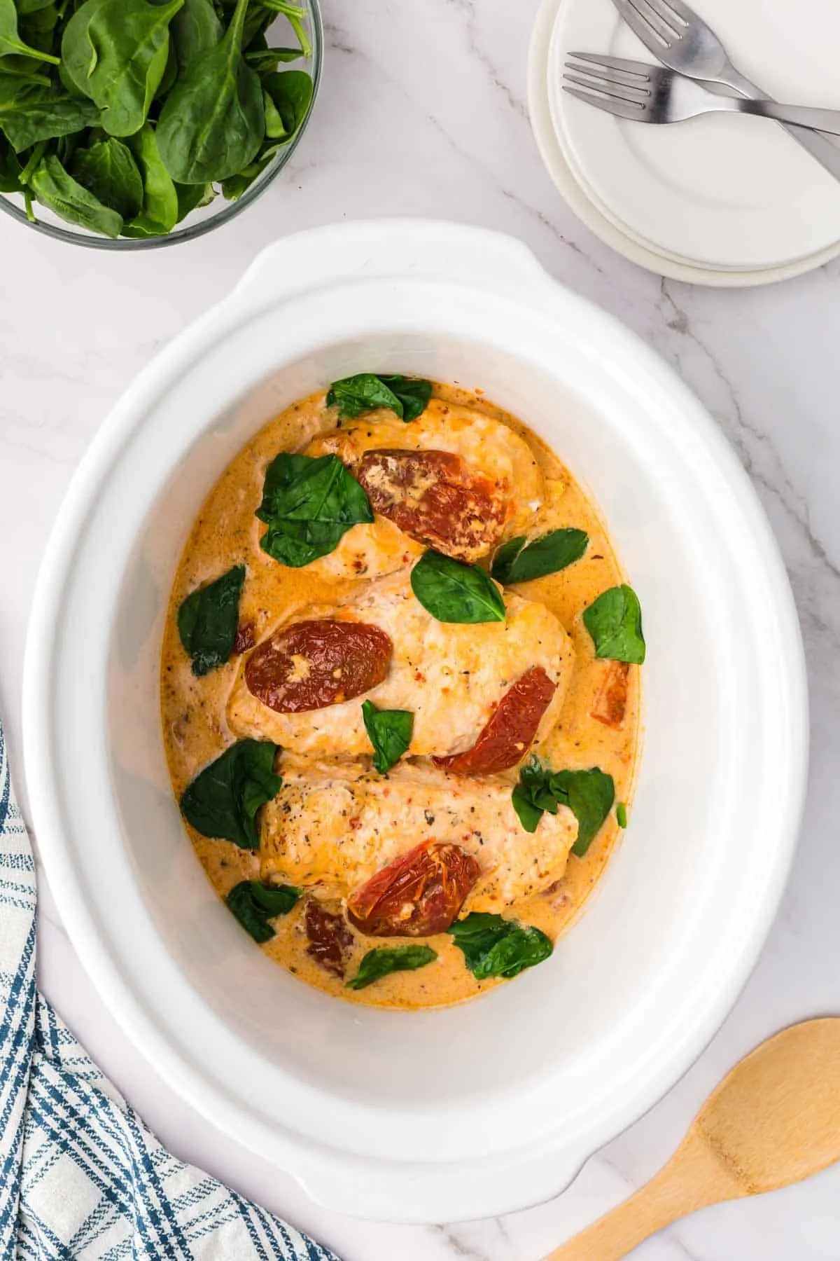Crock Pot Tuscan Chicken is an easy slow cooker chicken dinner recipe made with boneless, skinless chicken breasts and loaded with spinach, sundried tomatoes, cream of chicken soup, tomato sauce and parmesan cheese.