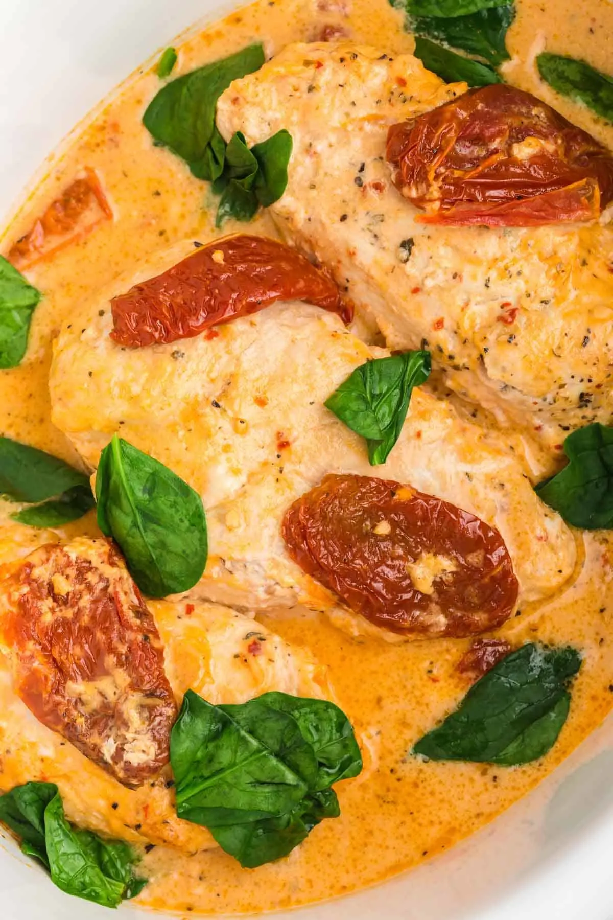 Crock Pot Tuscan Chicken is an easy slow cooker chicken dinner recipe made with boneless, skinless chicken breasts and loaded with spinach, sundried tomatoes, cream of chicken soup, tomato sauce and parmesan cheese.