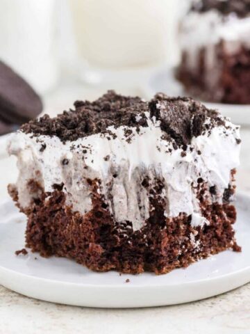 Oreo Poke Cake is a a simple but decadent cake recipe made with boxed chocolate cake mix, Oreo cookies n' creme pudding mix, milk, Cool Whip and Oreo cookies.