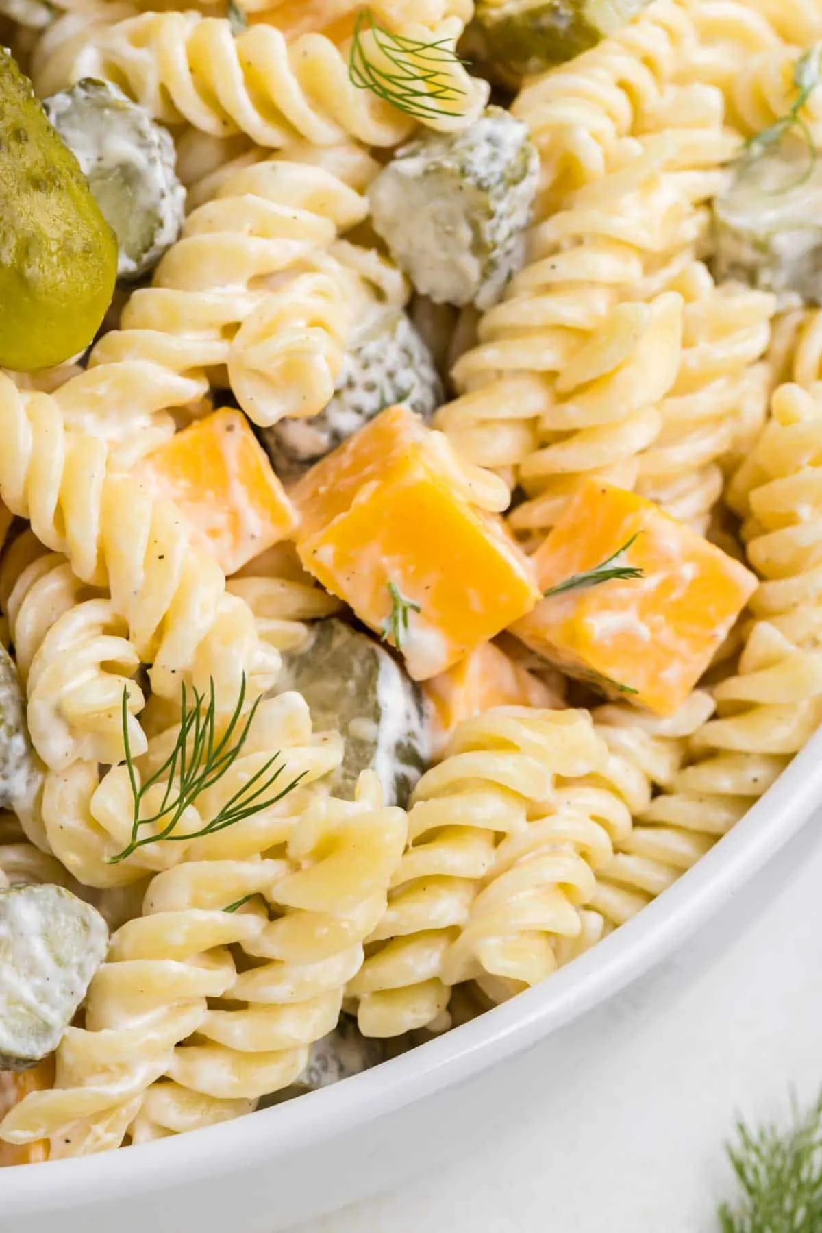 Dill Pickle Pasta Salad is a tasty cold side dish recipe made with rotini noodles and loaded with cheddar cheese, dill pickles and fresh dill all tossed in a mayo, sour cream and pickle juice dressing.