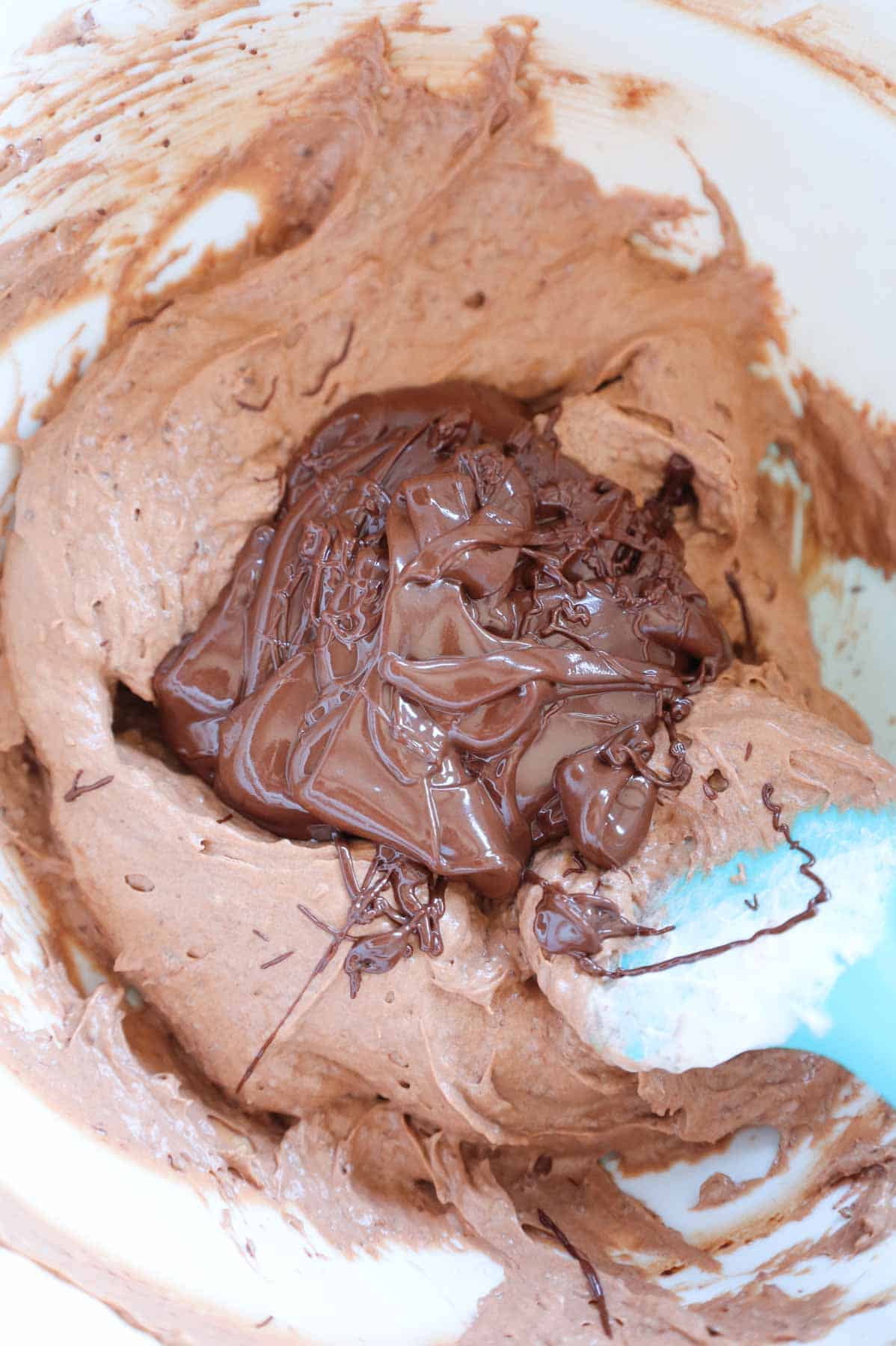 melted chocolate on top of chocolate pudding mixture in a mixing bowl