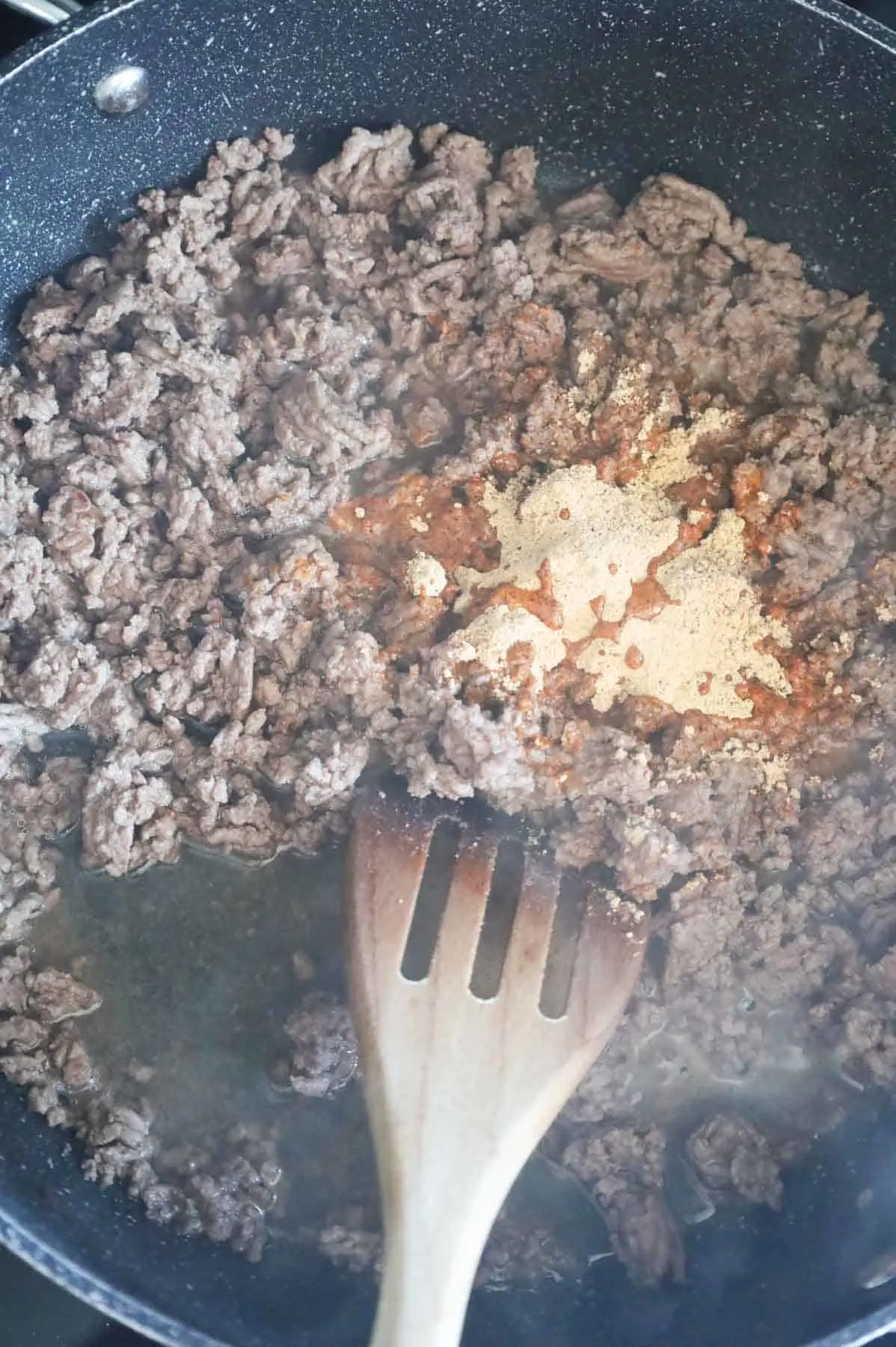 taco seasoning and water added to skillet with cooked ground beef