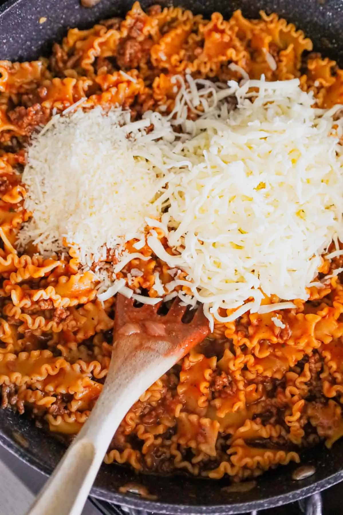 shredded mozzarella and parmesan added to skillet with tomato and ground beef pasta