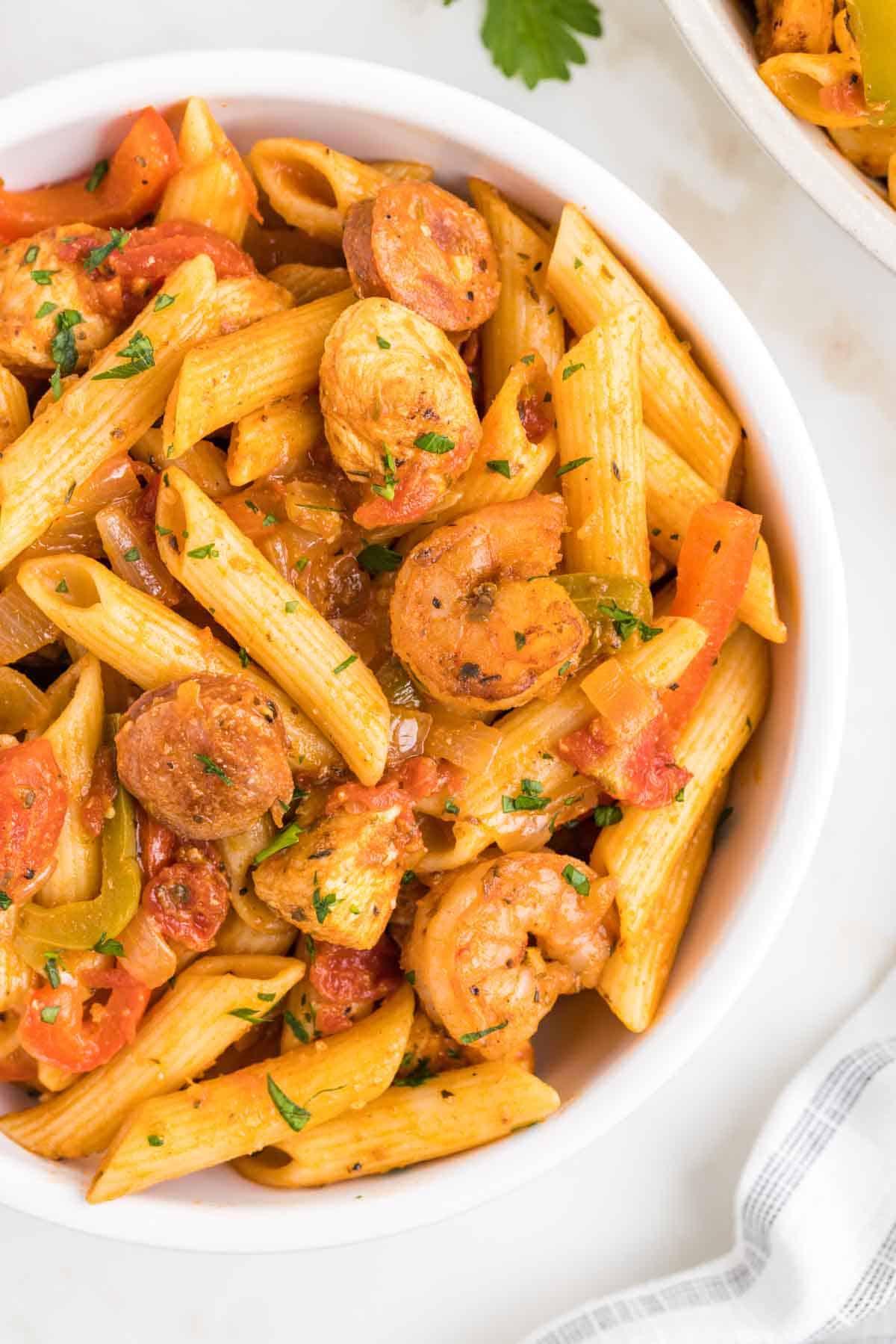 Jambalaya Pasta is a hearty penne pasta recipe loaded with bell peppers, shrimp, chicken breast chunks and andouille sausage all tossed in a tomato based sauce with a kick from some Cajun seasoning.