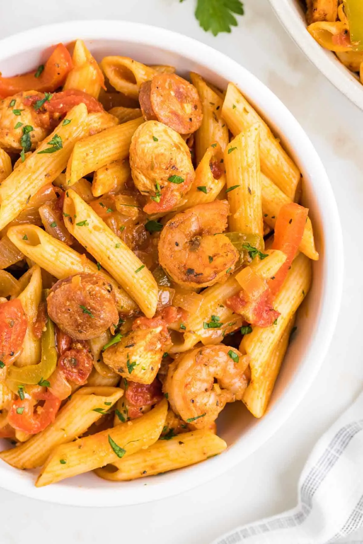 Jambalaya Pasta is a hearty penne pasta recipe loaded with bell peppers, shrimp, chicken breast chunks and andouille sausage all tossed in a tomato based sauce with a kick from some Cajun seasoning.