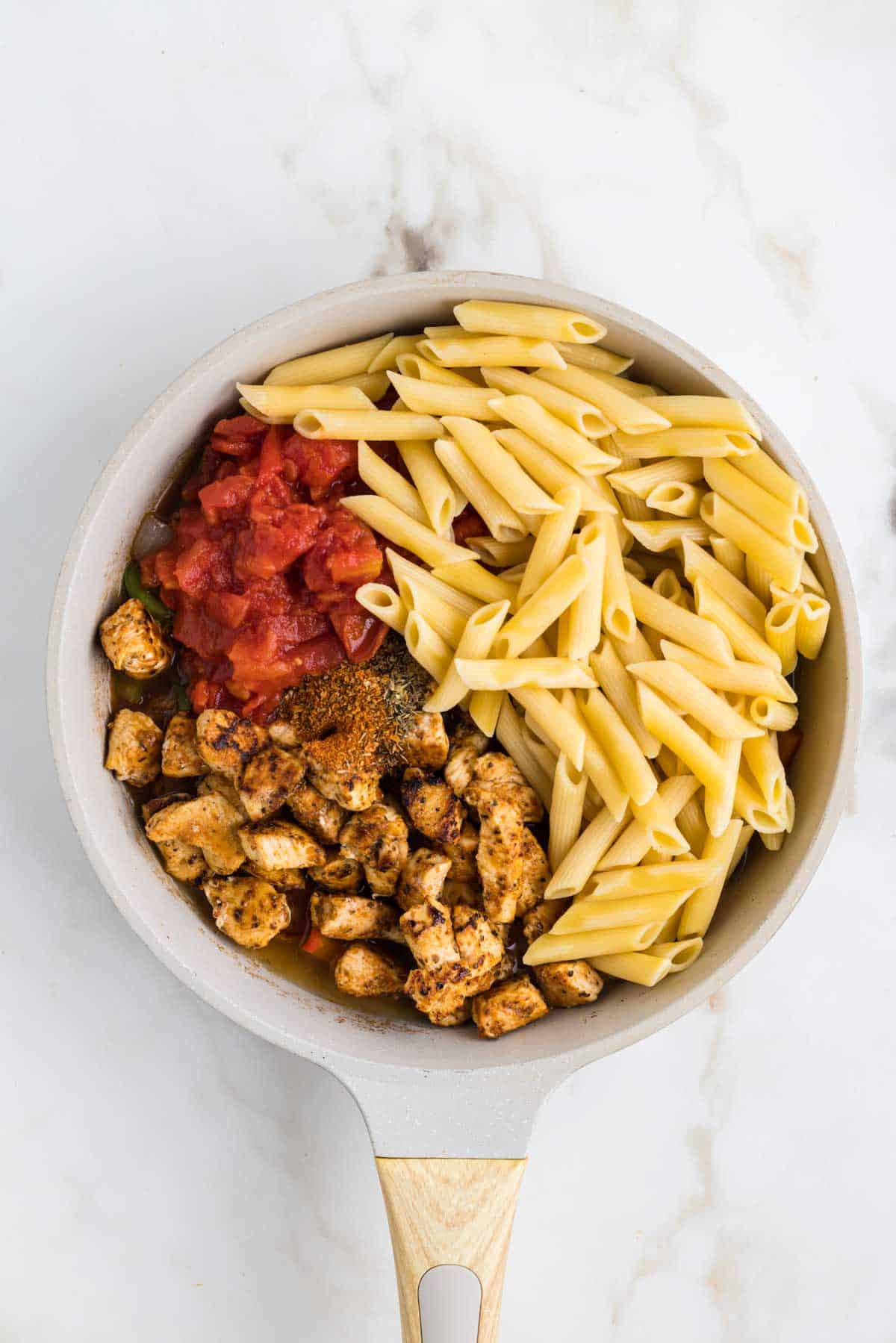 cooked penne noodles, canned tomatoes and cooked chicken added to skillet