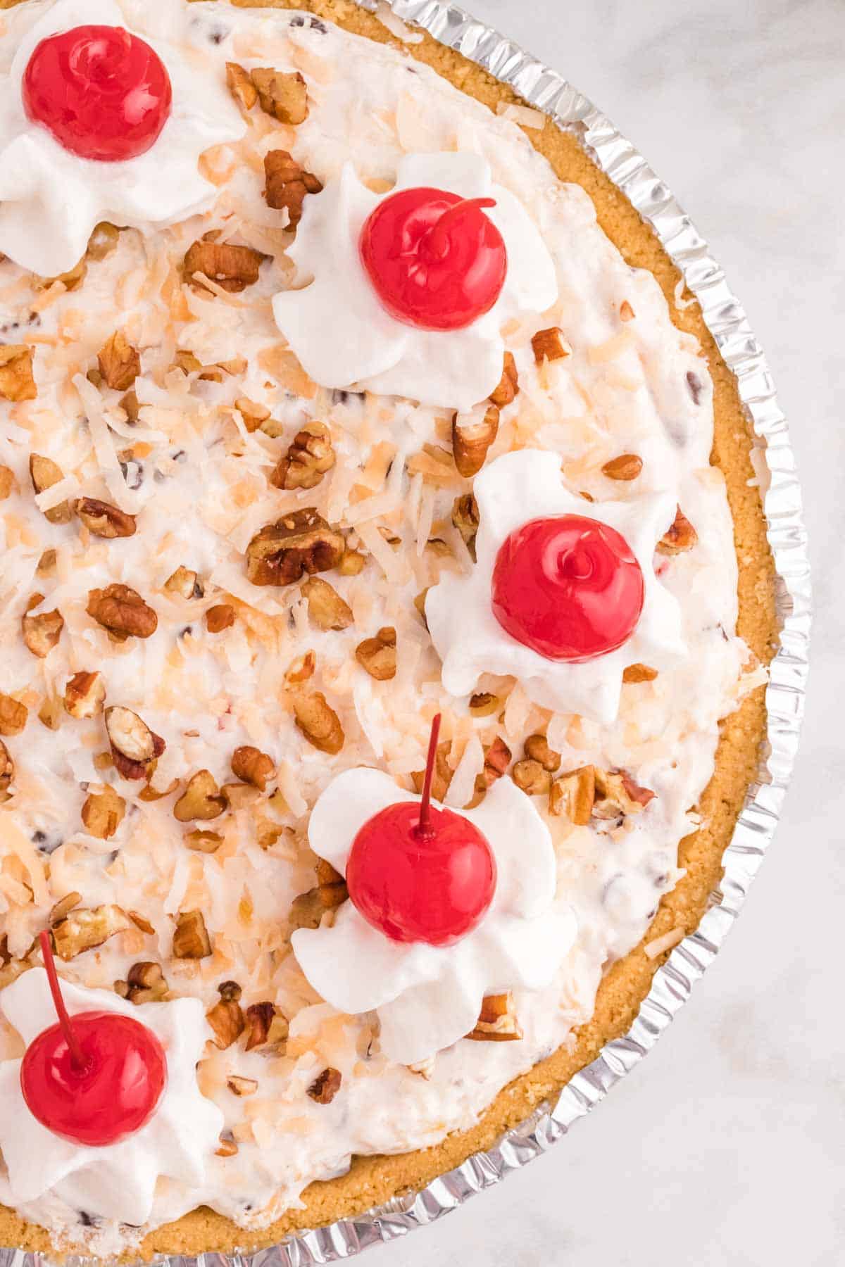 Million Dollar Pie is a creamy no bake pie loaded with crushed pineapple, chopped pecans, toasted coconut, maraschino cherries, mini marshmallows and chocolate chips all in a graham cracker crust.