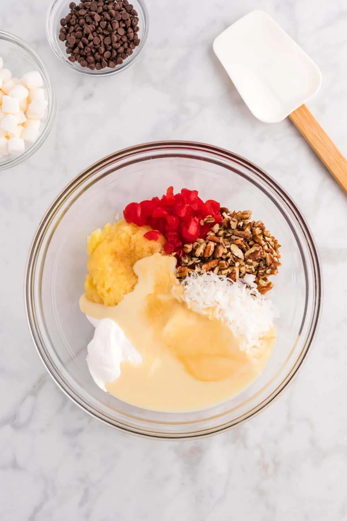 sweetened condensed milk, crushed pineapple, Cool Whip, shredded coconut, chopped pecans and chopped cherries in a bowl
