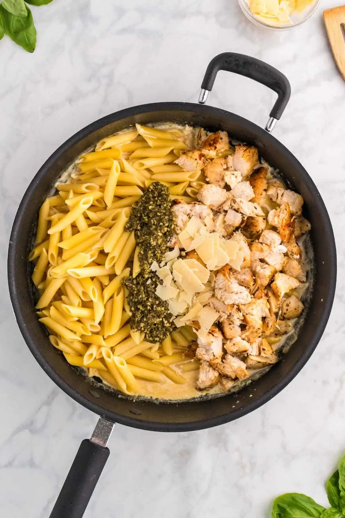 cooked penne, basil pesto, parmesan cheese and cooked sliced chicken breast pieces added to skillet