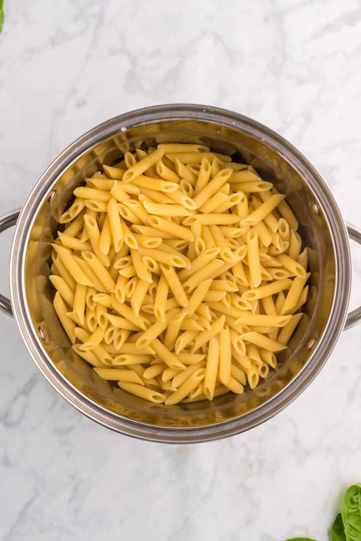 cooked penne pasta in a colander