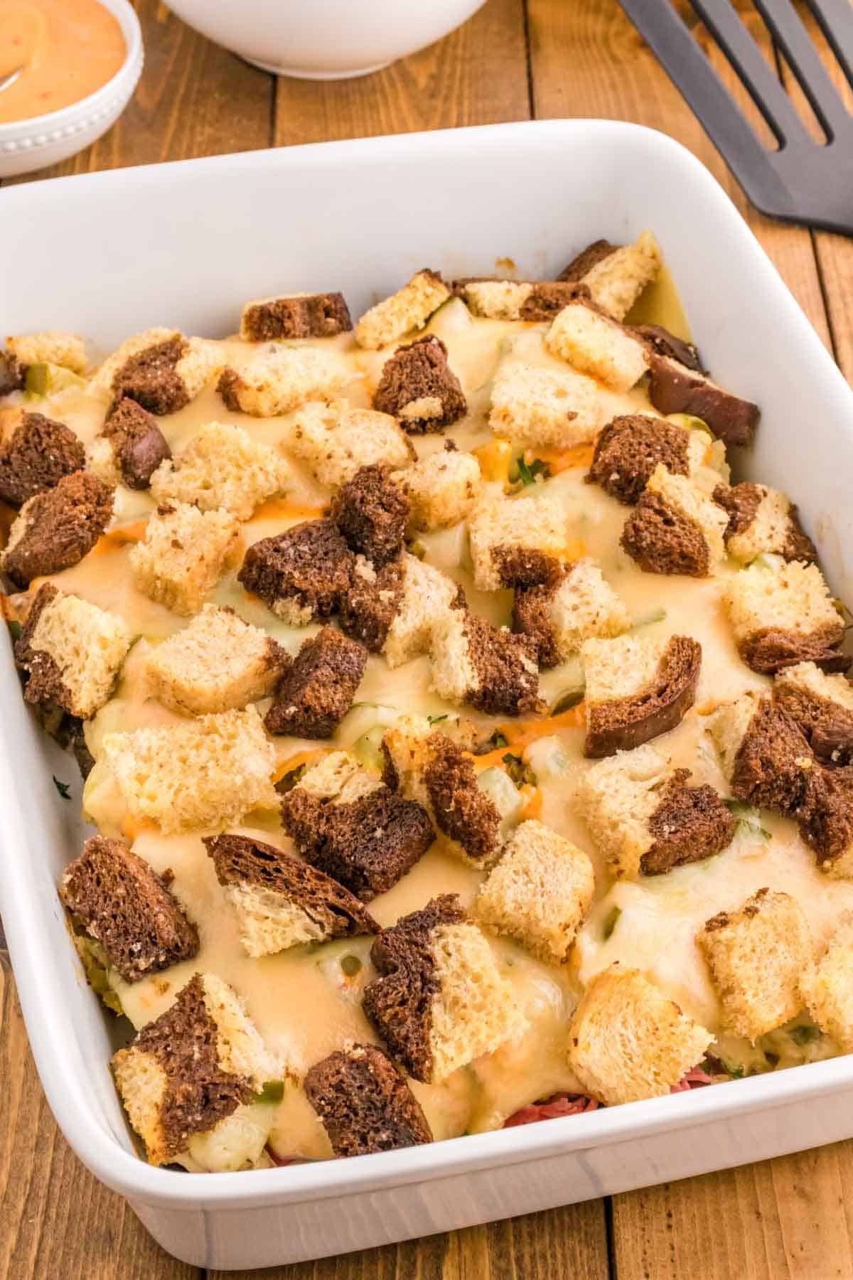 Reuben Casserole is a tasty dish loaded with cubes of rye bread, sliced corned beef, sauerkraut, dill pickles, Swiss cheese and Thousand Island dressing.