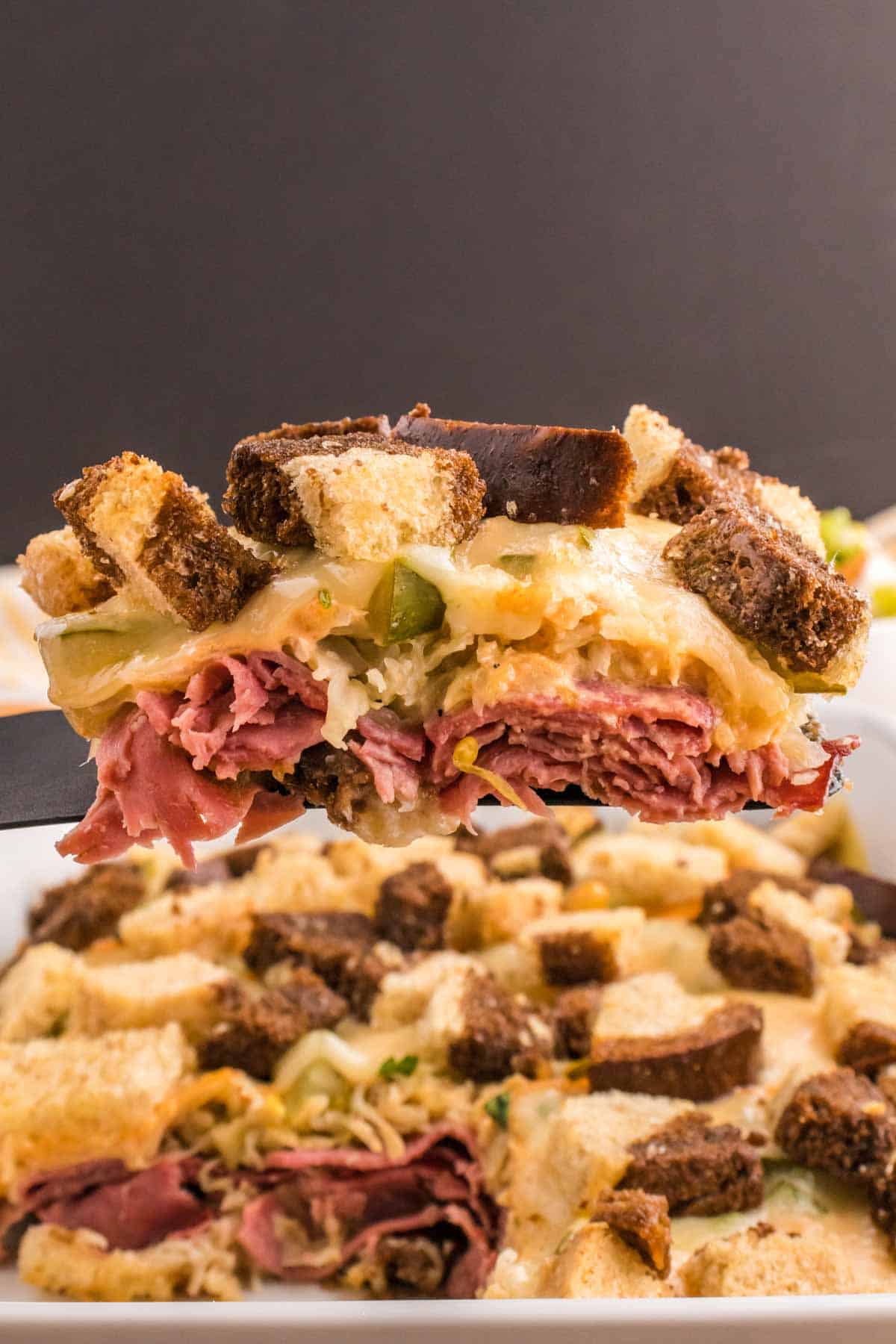 Reuben Casserole is a tasty dish loaded with cubes of rye bread, sliced corned beef, sauerkraut, dill pickles, Swiss cheese and Thousand Island dressing.