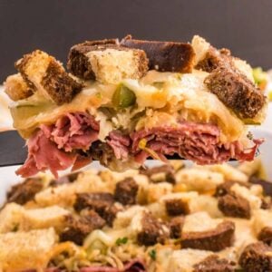 Reuben Casserole is a tasty dish loaded with cubes of rye bread, sliced corned beef, sauerkraut, dill pickles, Swiss cheese and Thousand Island dressing.