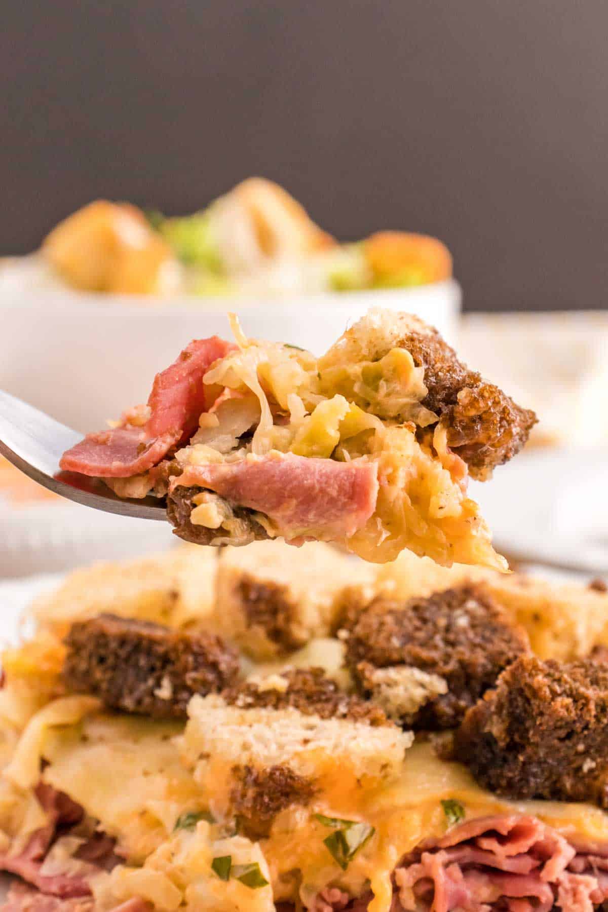 Reuben Casserole is a tasty dish loaded with cubes of rye bread, sliced corned beef, sauerkraut, dill pickles, Swiss cheese and Thousand Island dressing.