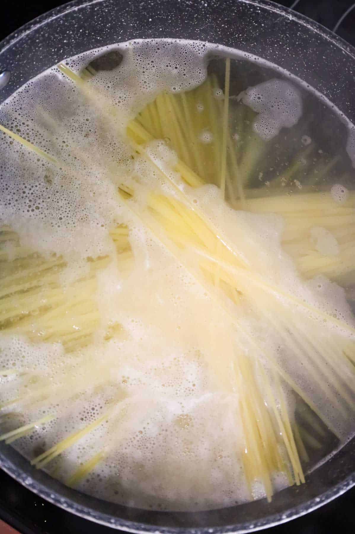 spaghetti noodles cooking in a pot of water