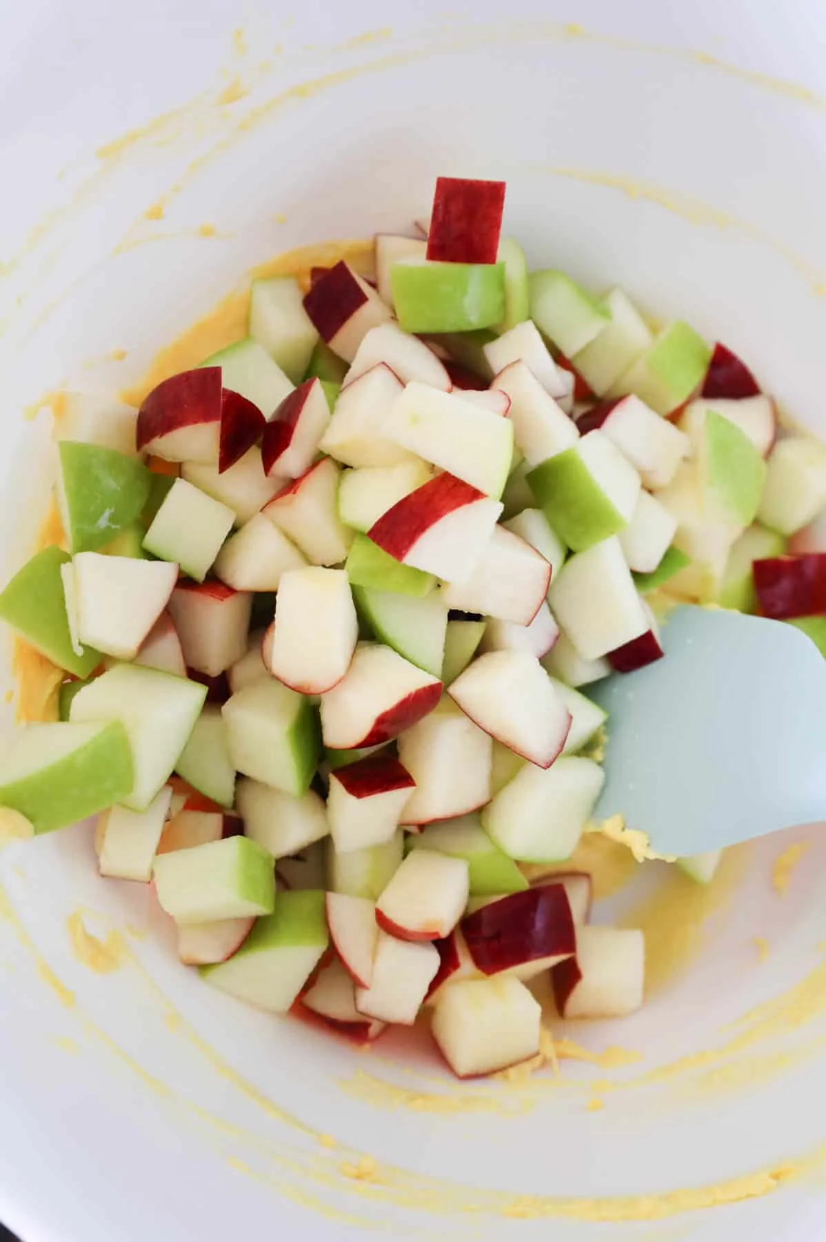 diced red and green apples added to a bowl with vanilla instant pudding