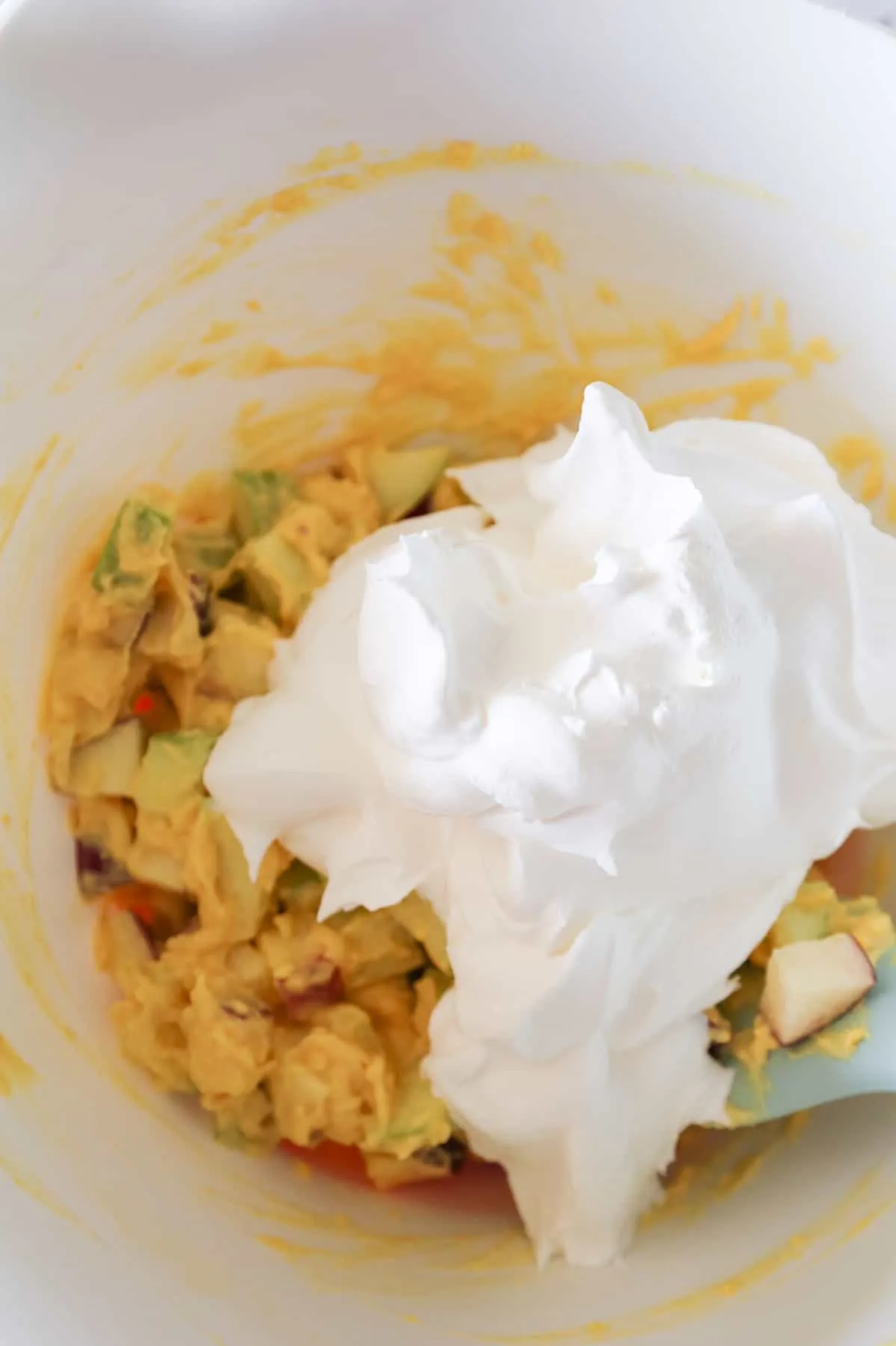 Cool Whip on top of diced apple and vanilla pudding mixture in a bowl