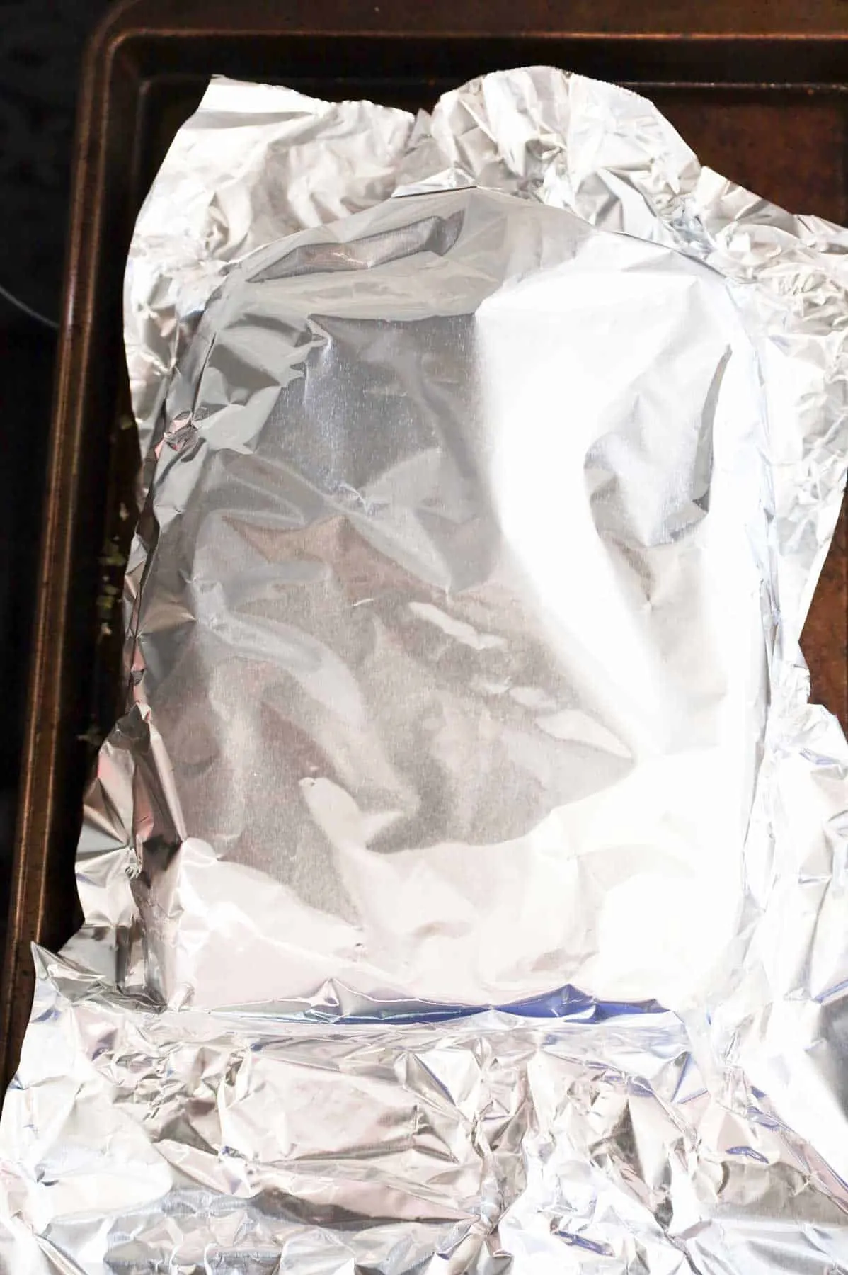 aluminum foil covering turkey bacon sliders on a baking sheet