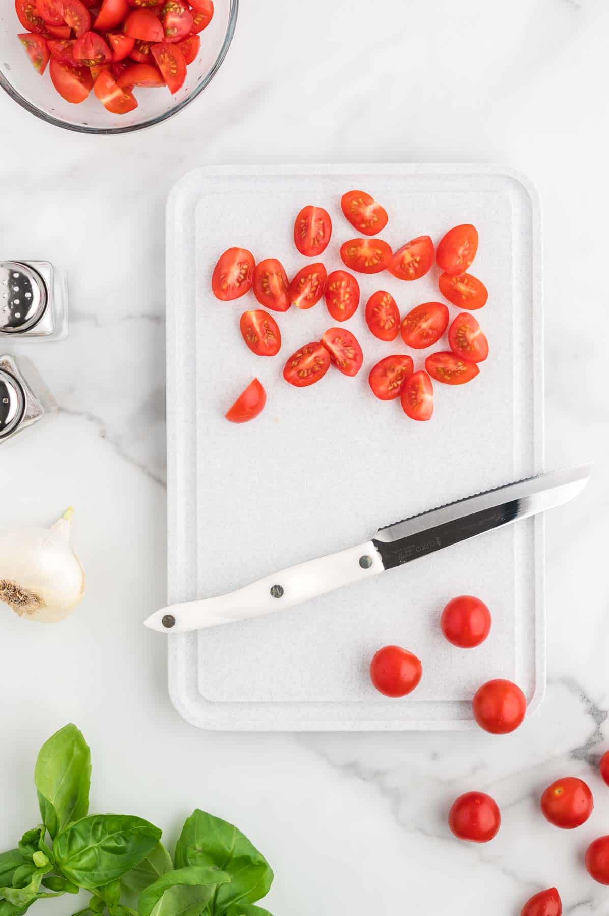 quartered cherry tomatoes on a cutting board