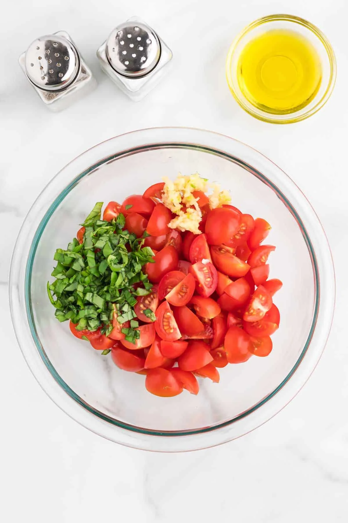 chopped basil leaves, minced garlic and quartered cherry tomatoes in a mixing bowl